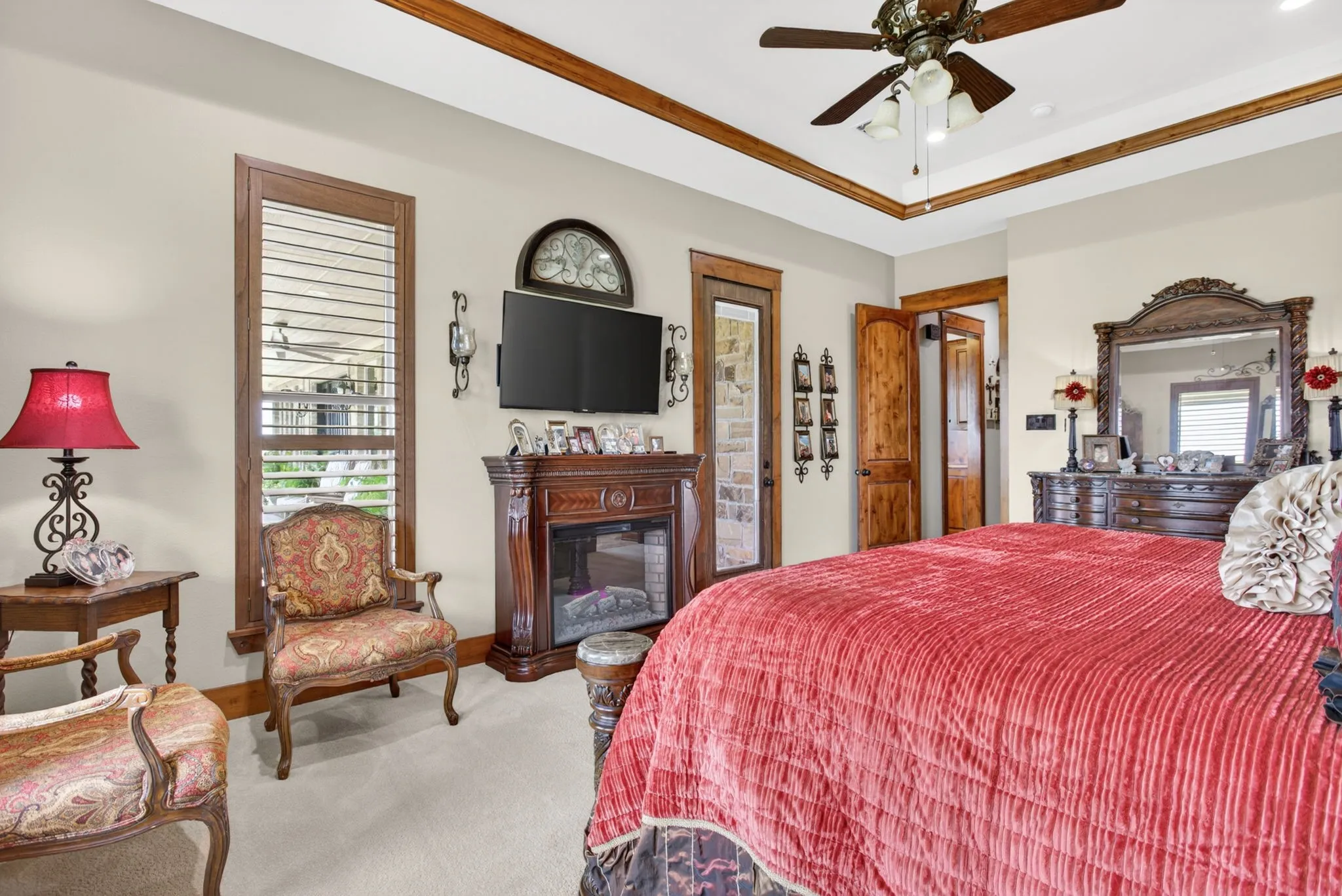 Spacious room featuring a tray ceiling with wood-finish trim, a ceiling fan, and carpeted flooring