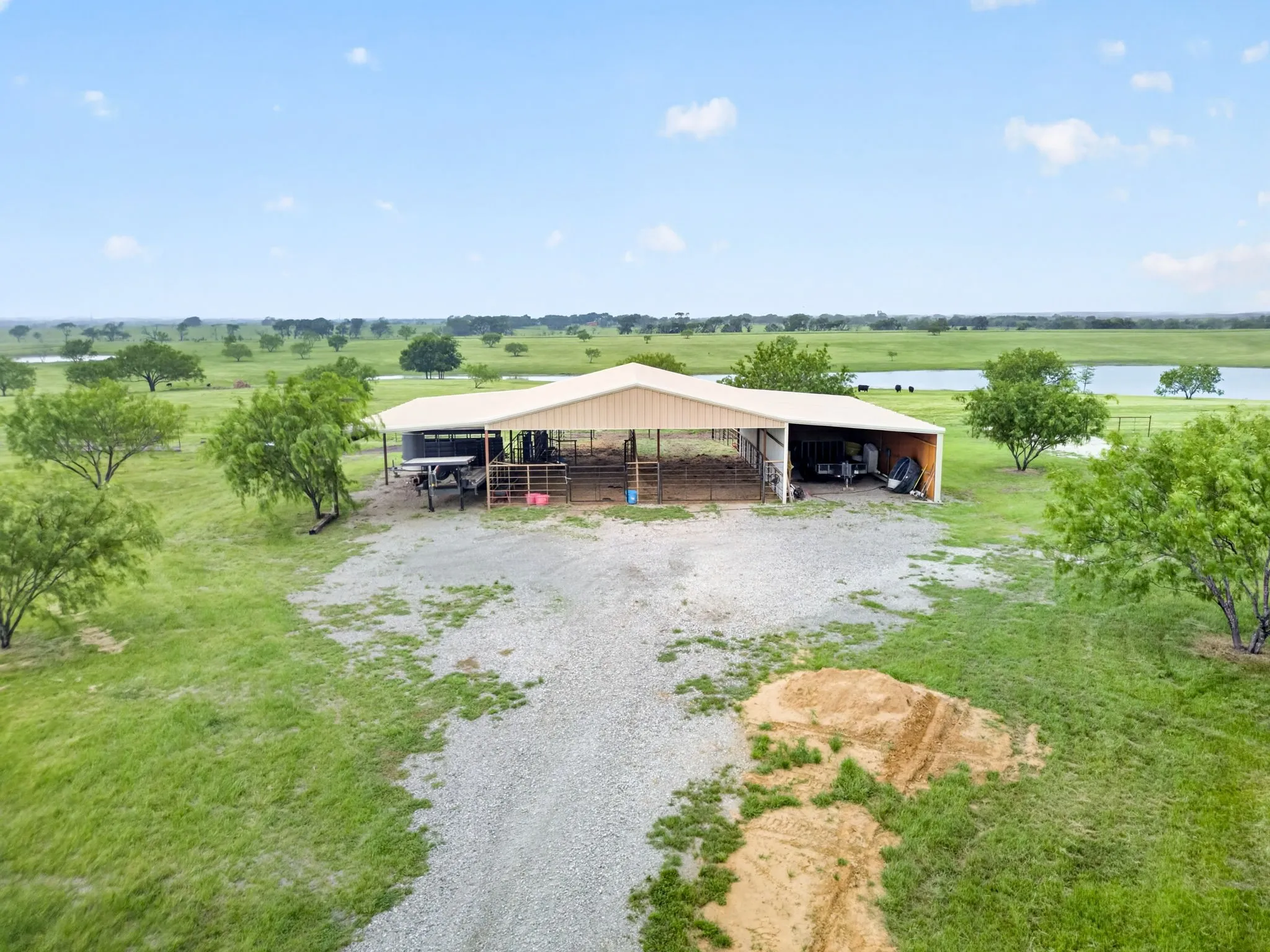 Expansive metal barn structure featuring an open-sided design, large covered areas, and partitioned interior spaces