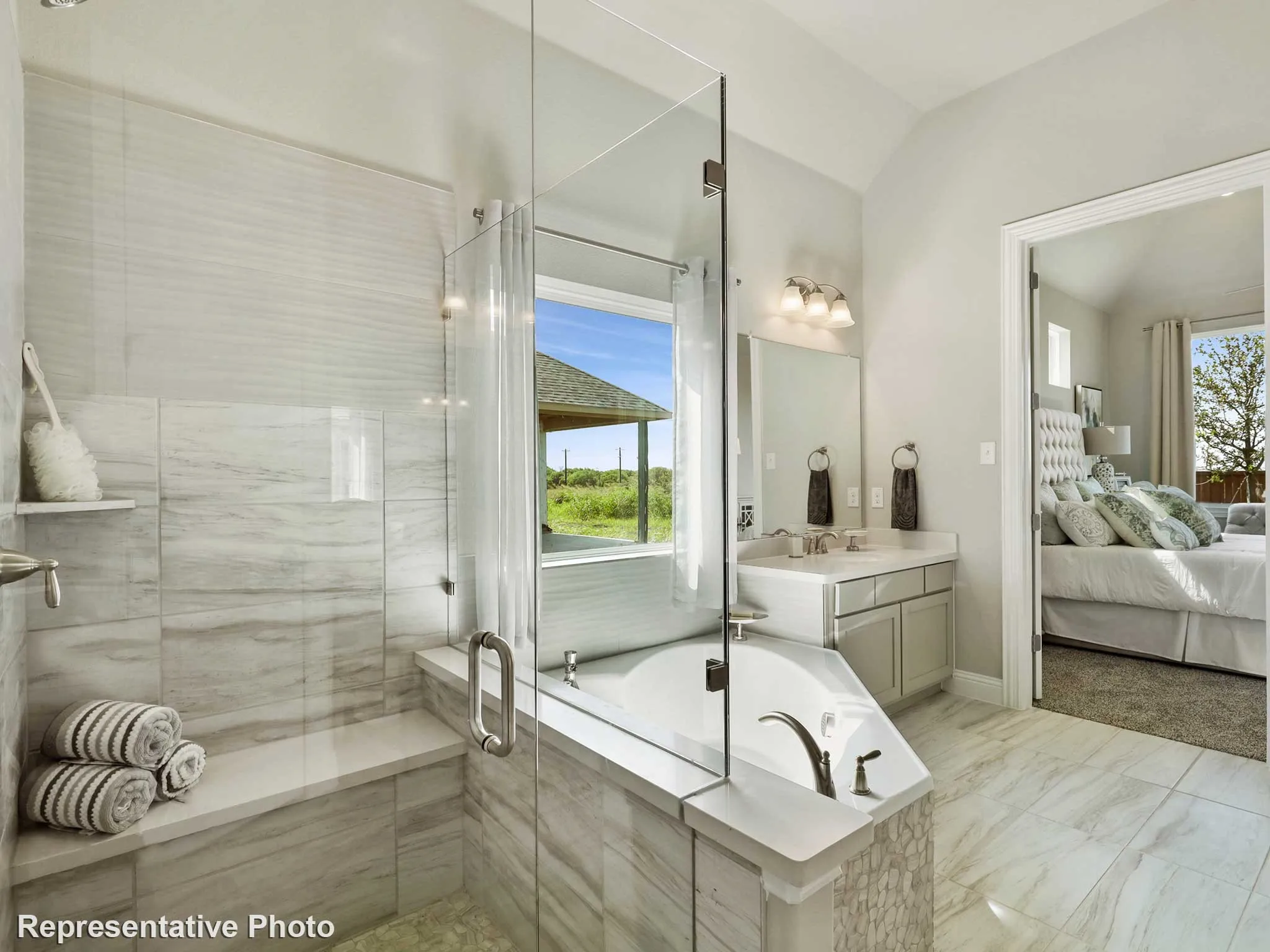Bathroom featuring a soaking tub, glass-enclosed shower with a built-in bench, dual vanity, tiled flooring, and a vaulted ceiling