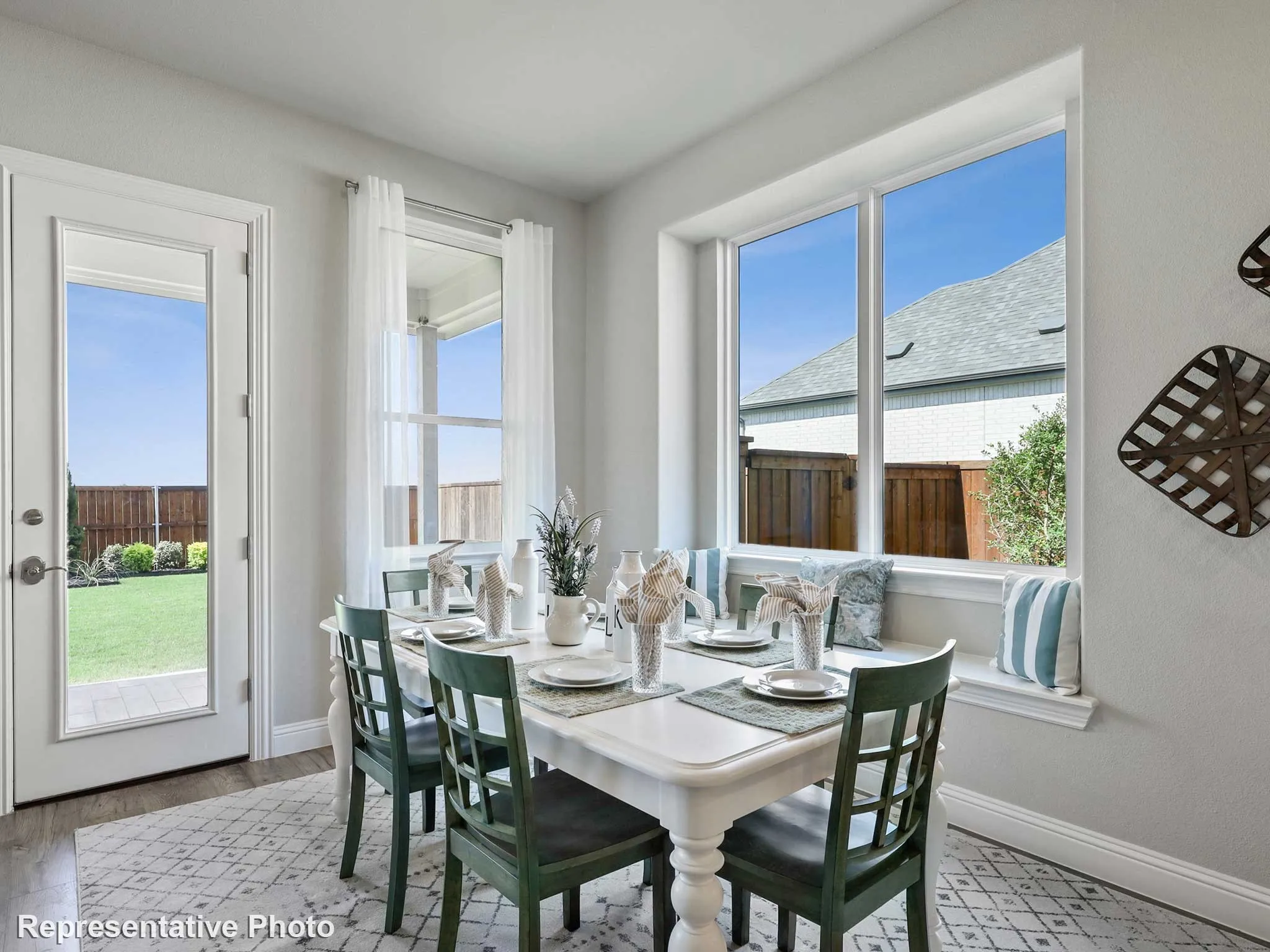 Bright dining area featuring a built-in window bench, large picture windows, and a glass-paneled door