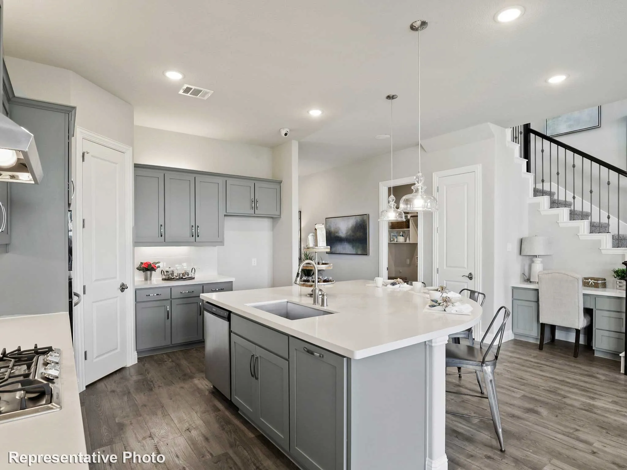 Open-concept kitchen featuring gray shaker-style cabinetry, a spacious island with a countertop, wood-finish flooring, and recessed lighting