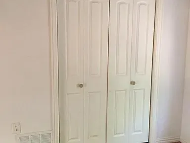 White bi-fold closet doors with round brass knobs, framed by white trim