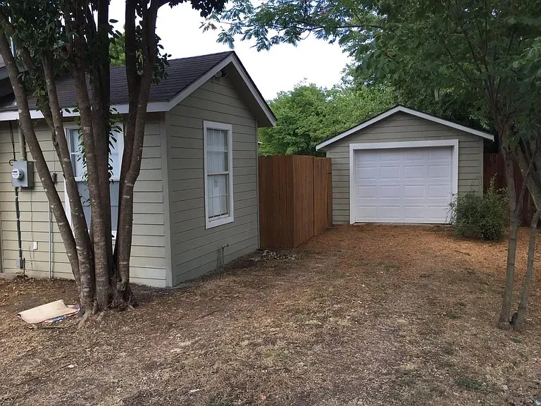Detached garage with a white panel door and light green siding
