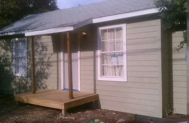 Light green horizontal siding with a newly constructed wood deck and porch cover