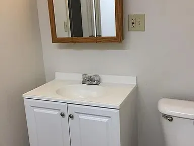 White vanity cabinet with a single basin sink, chrome faucet, and integrated countertop