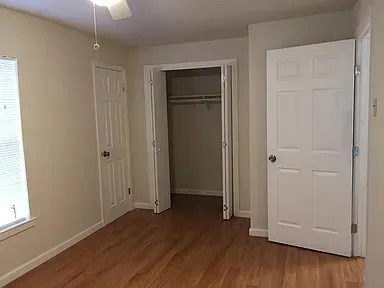 Room featuring wood-finish flooring, a ceiling fan, and a window with horizontal blinds