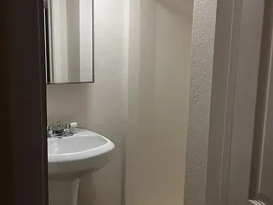 Pedestal sink with chrome-finish faucet and wall-mounted mirrored medicine cabinet
