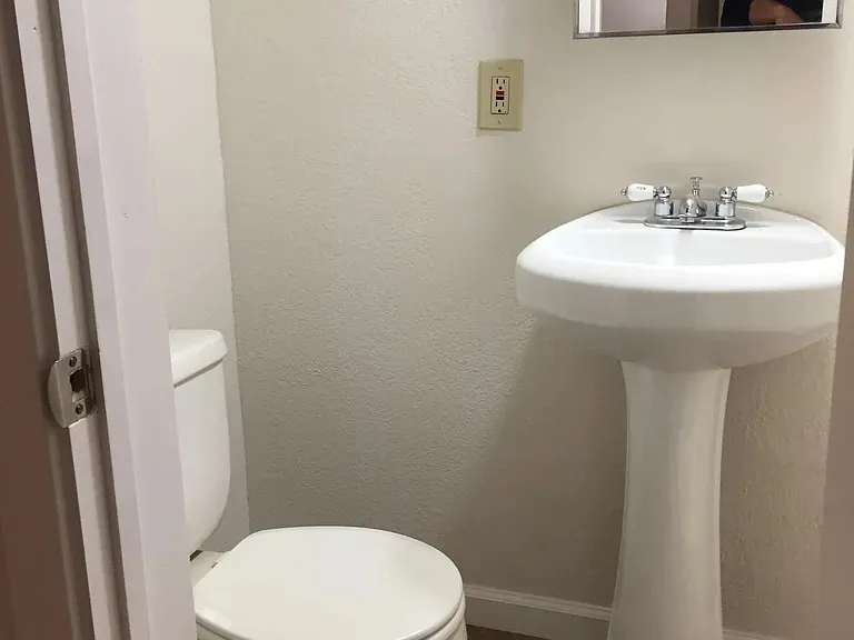 Pedestal sink with chrome faucet hardware and white ceramic handles