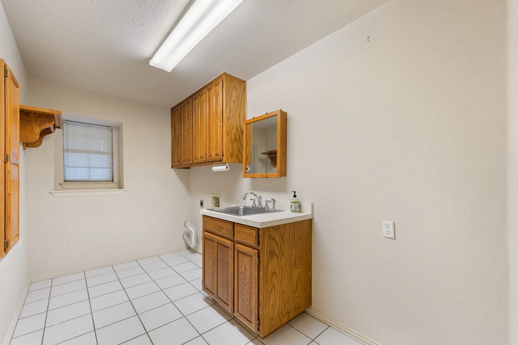 Utility room featuring a built-in sink with a white countertop and wood-finish cabinetry