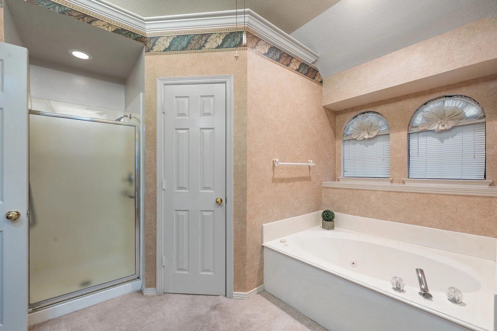 Built-in jetted tub with chrome fixtures and arched windows above