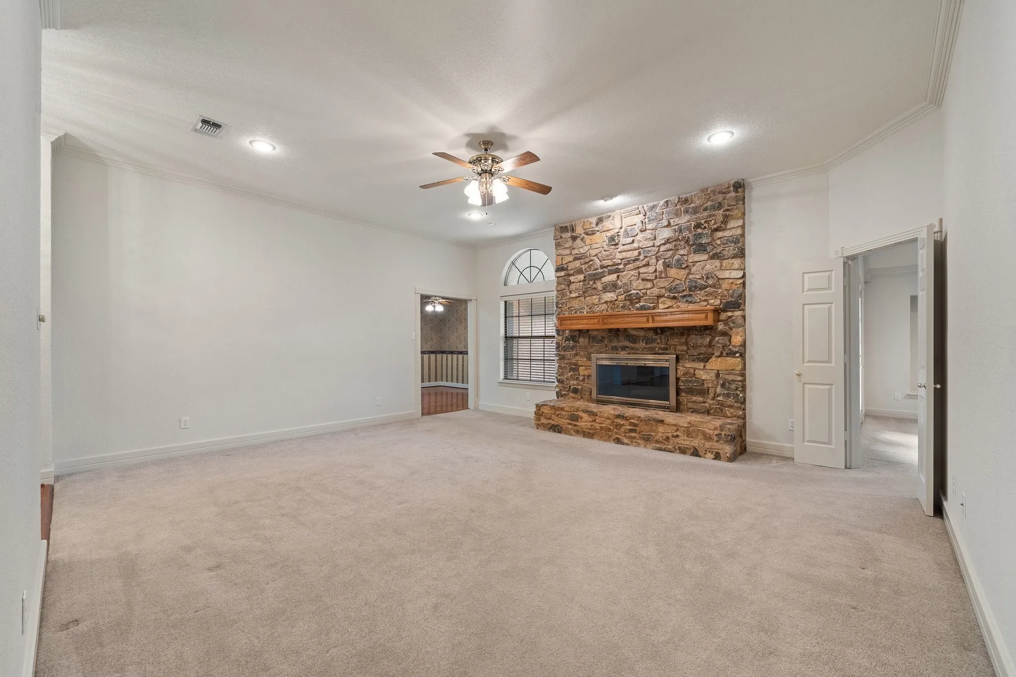 Spacious room featuring a prominent stone-clad fireplace with a wood mantel
