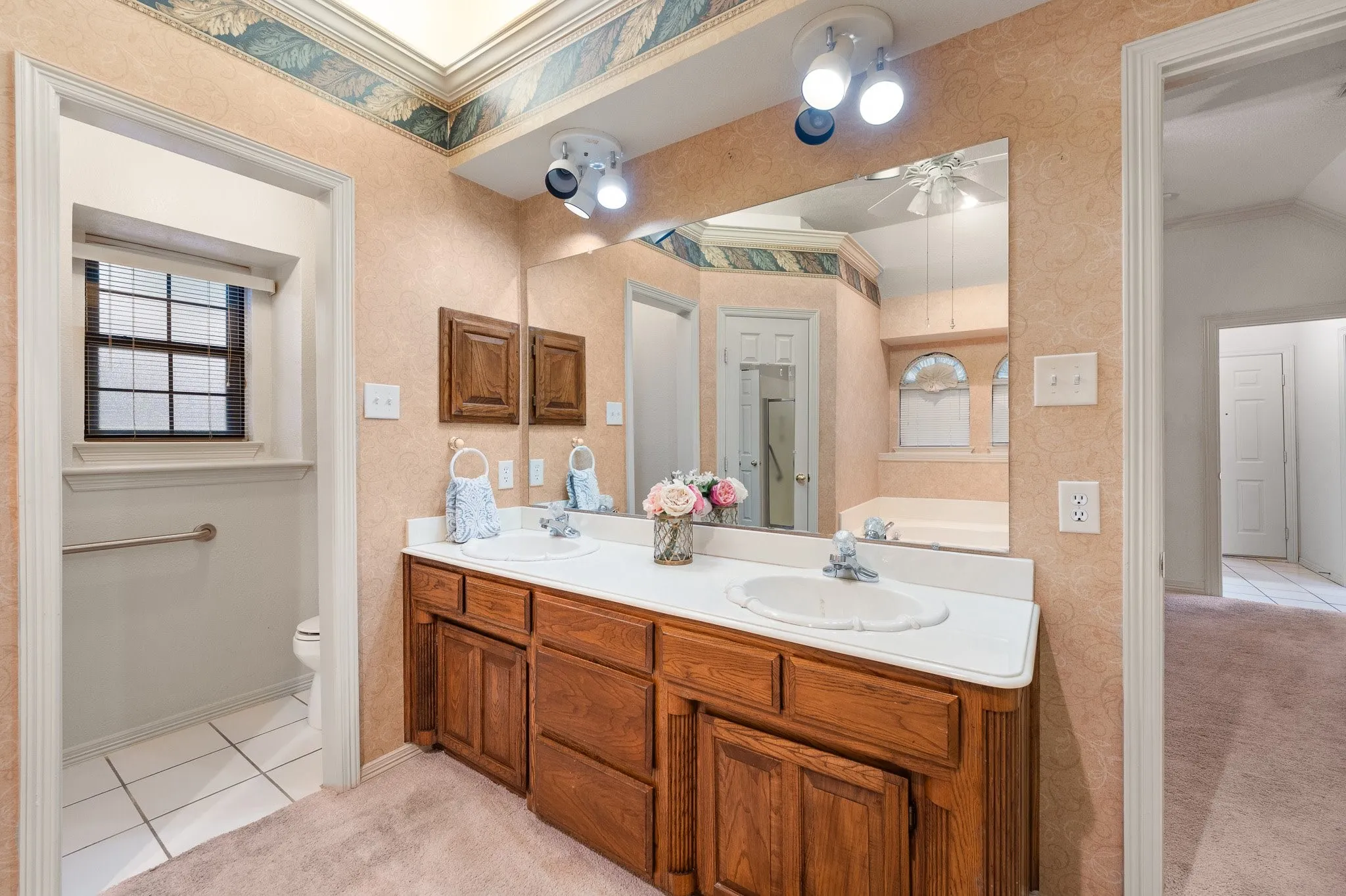 Bathroom featuring a dual-sink vanity with wood cabinetry and a large wall-mounted mirror