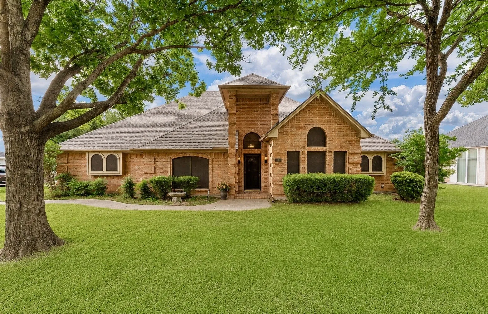 Brick facade residence with a gabled roofline and an arched entry