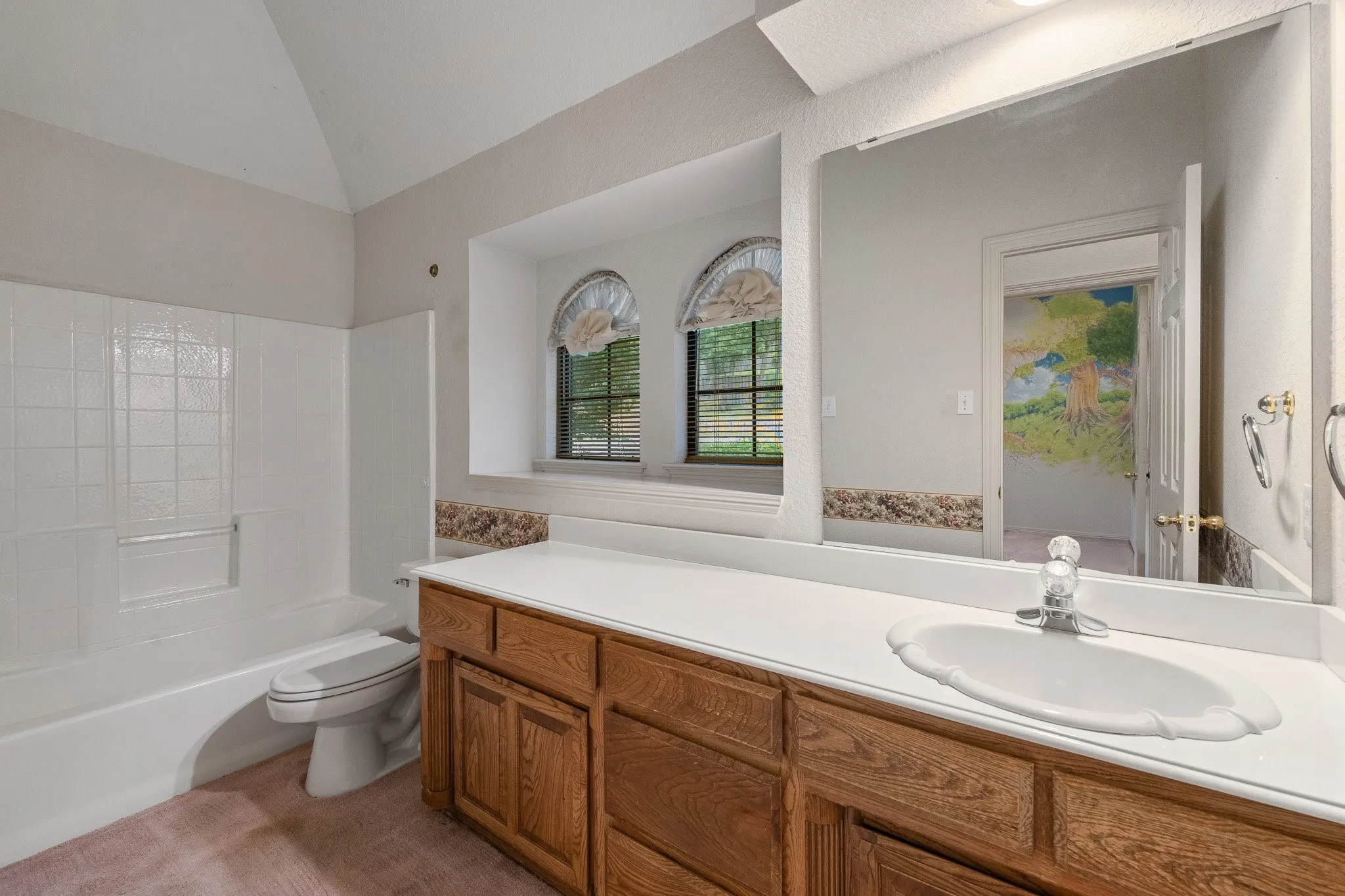 Bathroom featuring a single vanity with wood-finish cabinetry, a white countertop, and an oval undermount sink