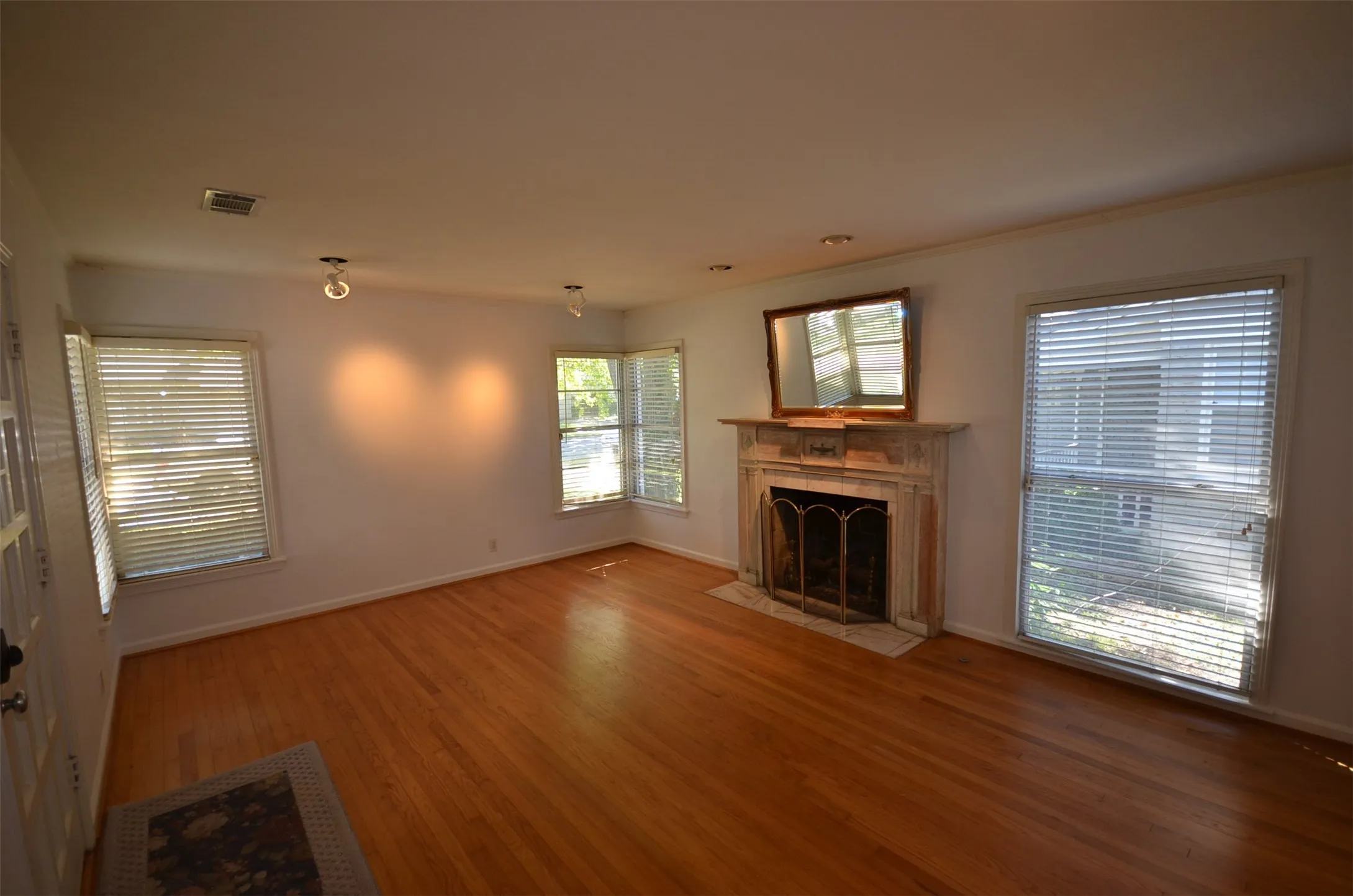 Hardwood flooring throughout, featuring a fireplace with a stone mantel and hearth