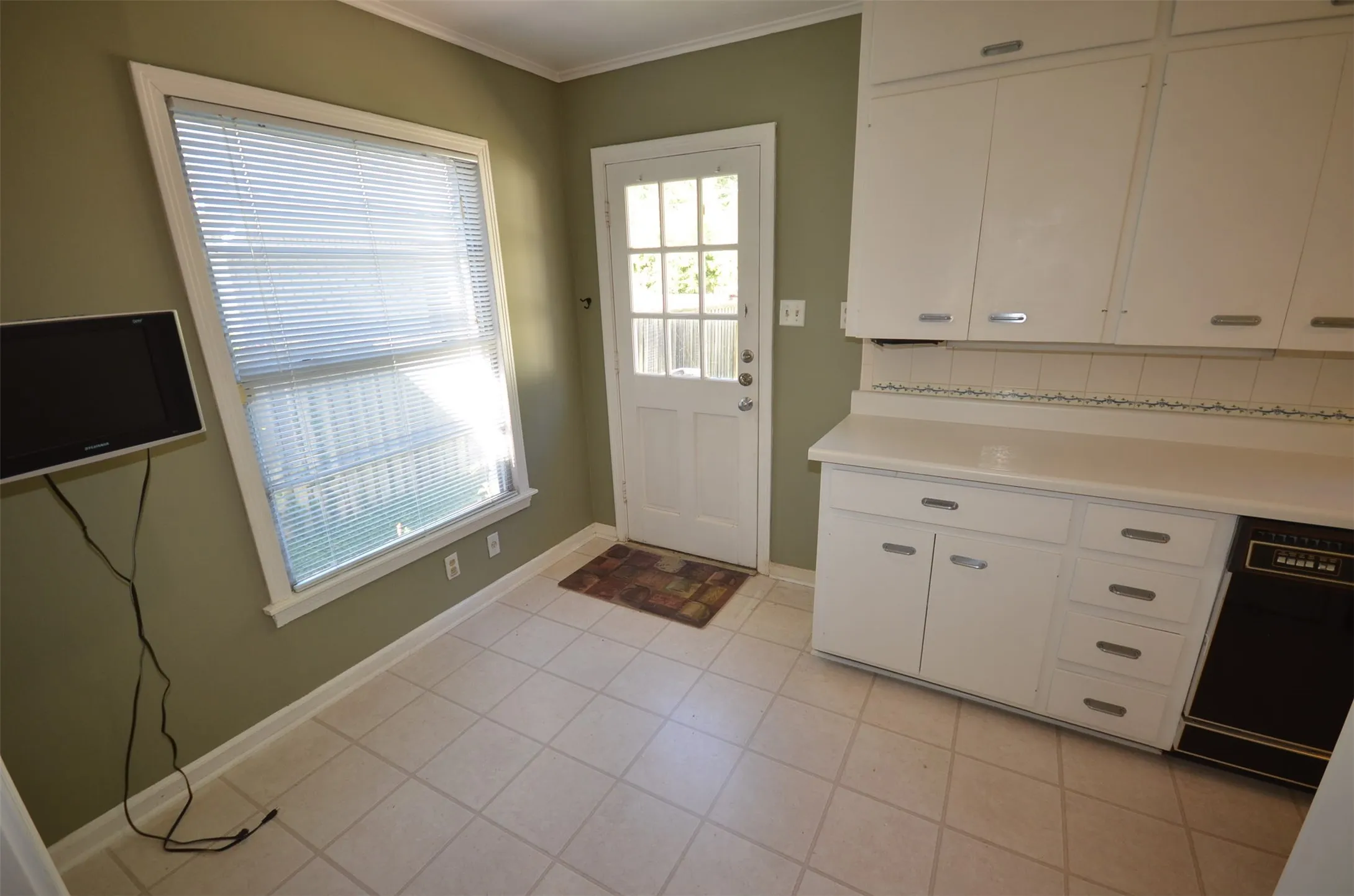 Kitchen space featuring white cabinetry with silver-tone hardware, a white countertop, and a white tile backsplash