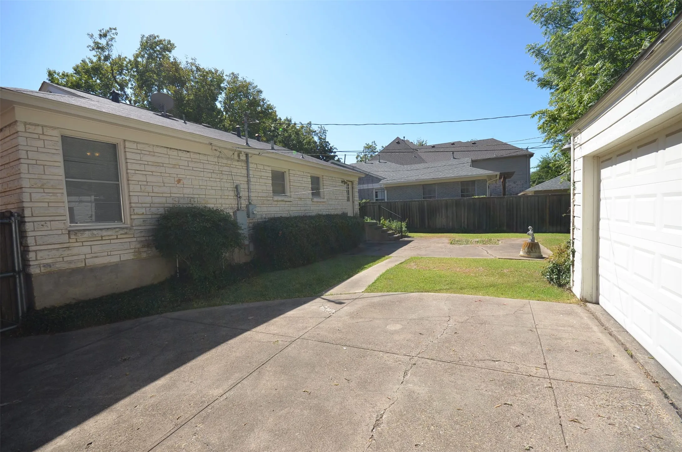 Rear exterior featuring a detached garage with a paneled door, a paved driveway, and a partially grassed yard
