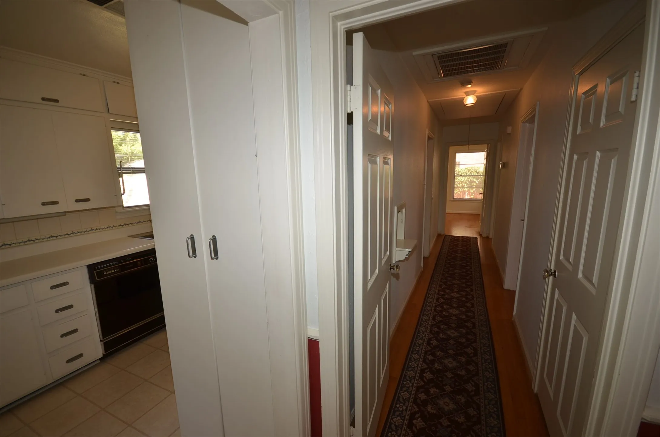 Corridor with wood-finish flooring, white paneled doors, and ceiling-mounted light fixtures