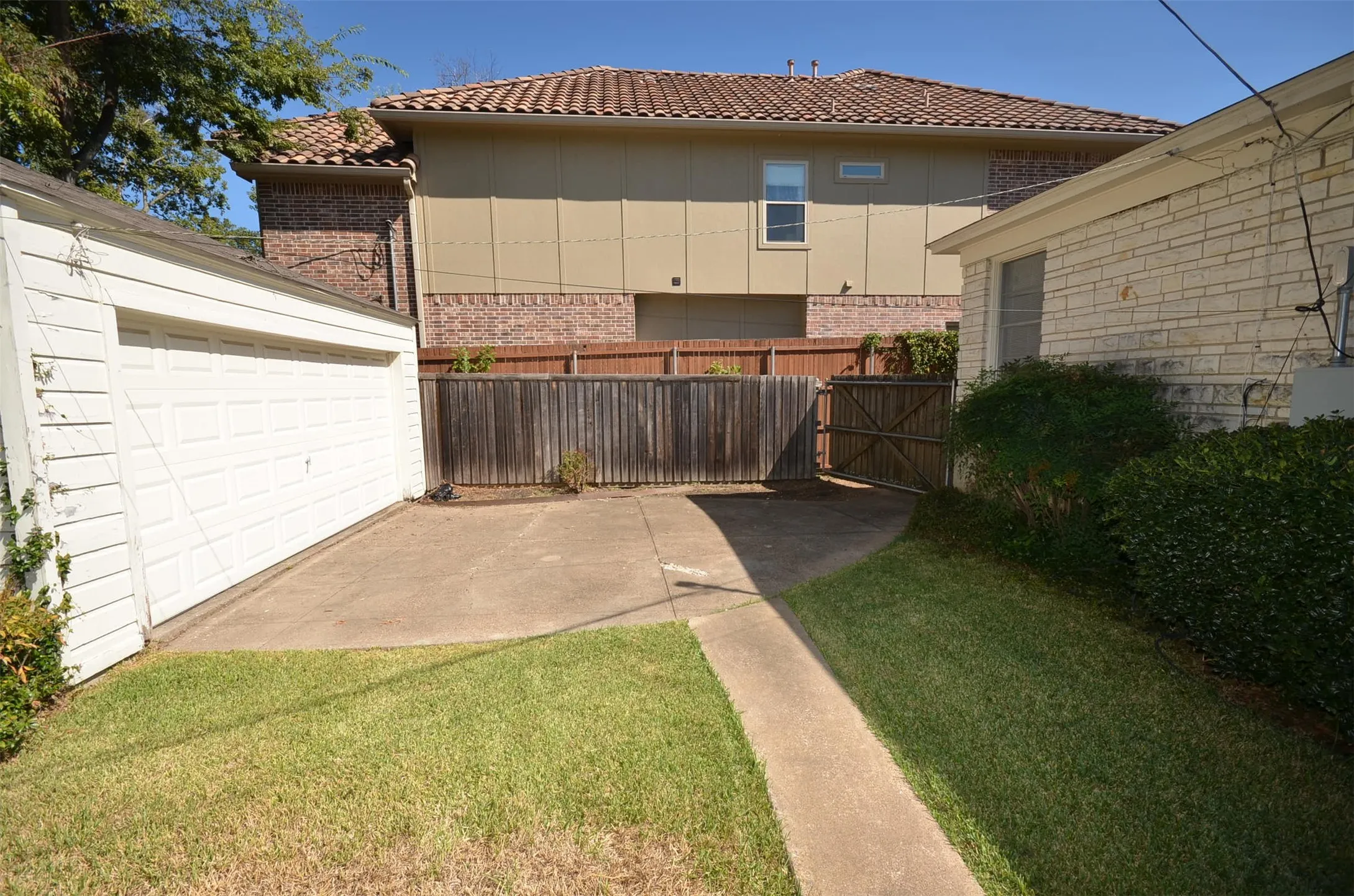 Detached garage with a paneled door, concrete driveway, and wood privacy fencing