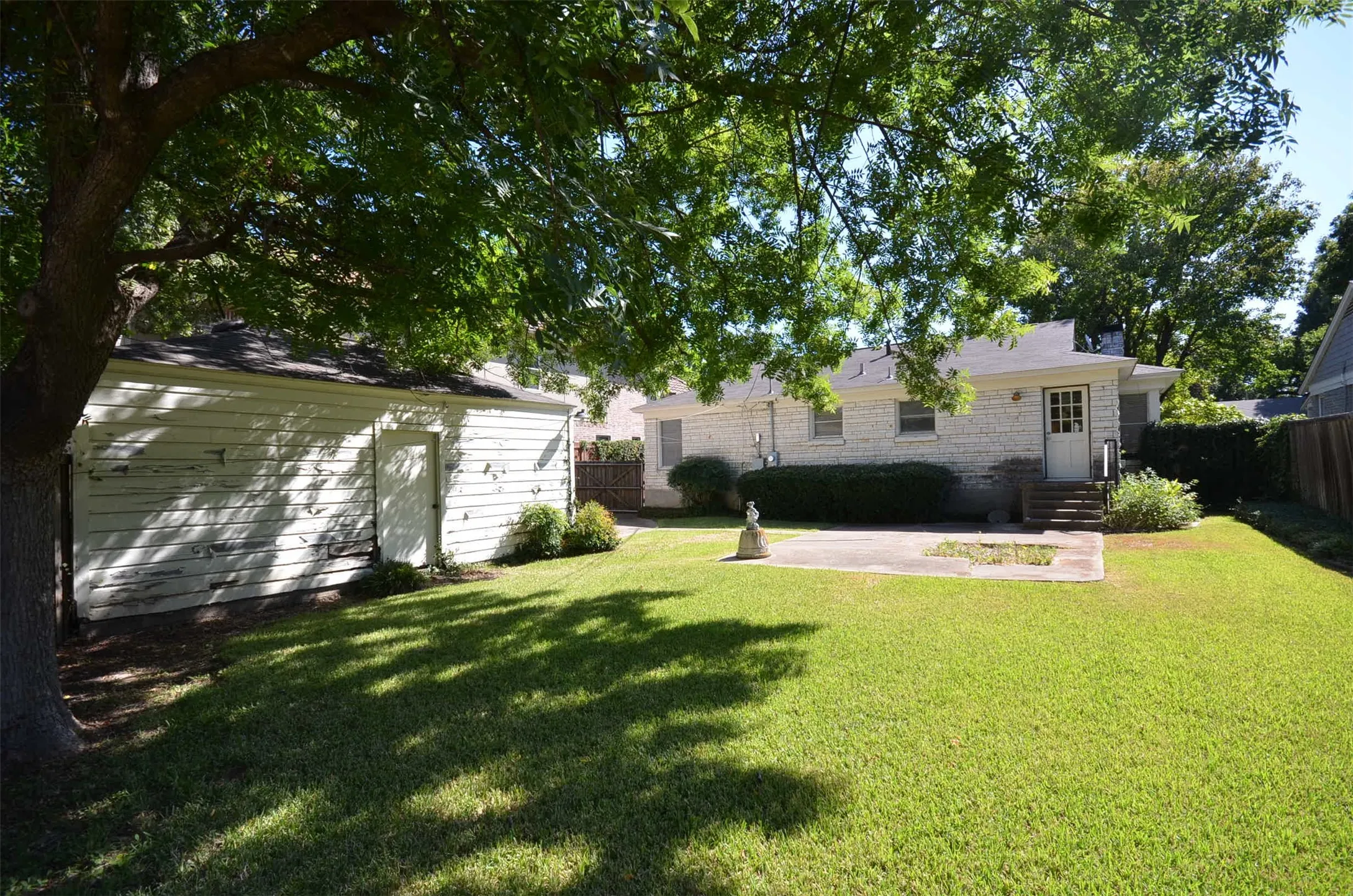 Expansive backyard featuring a manicured lawn, a concrete patio, and a detached auxiliary structure