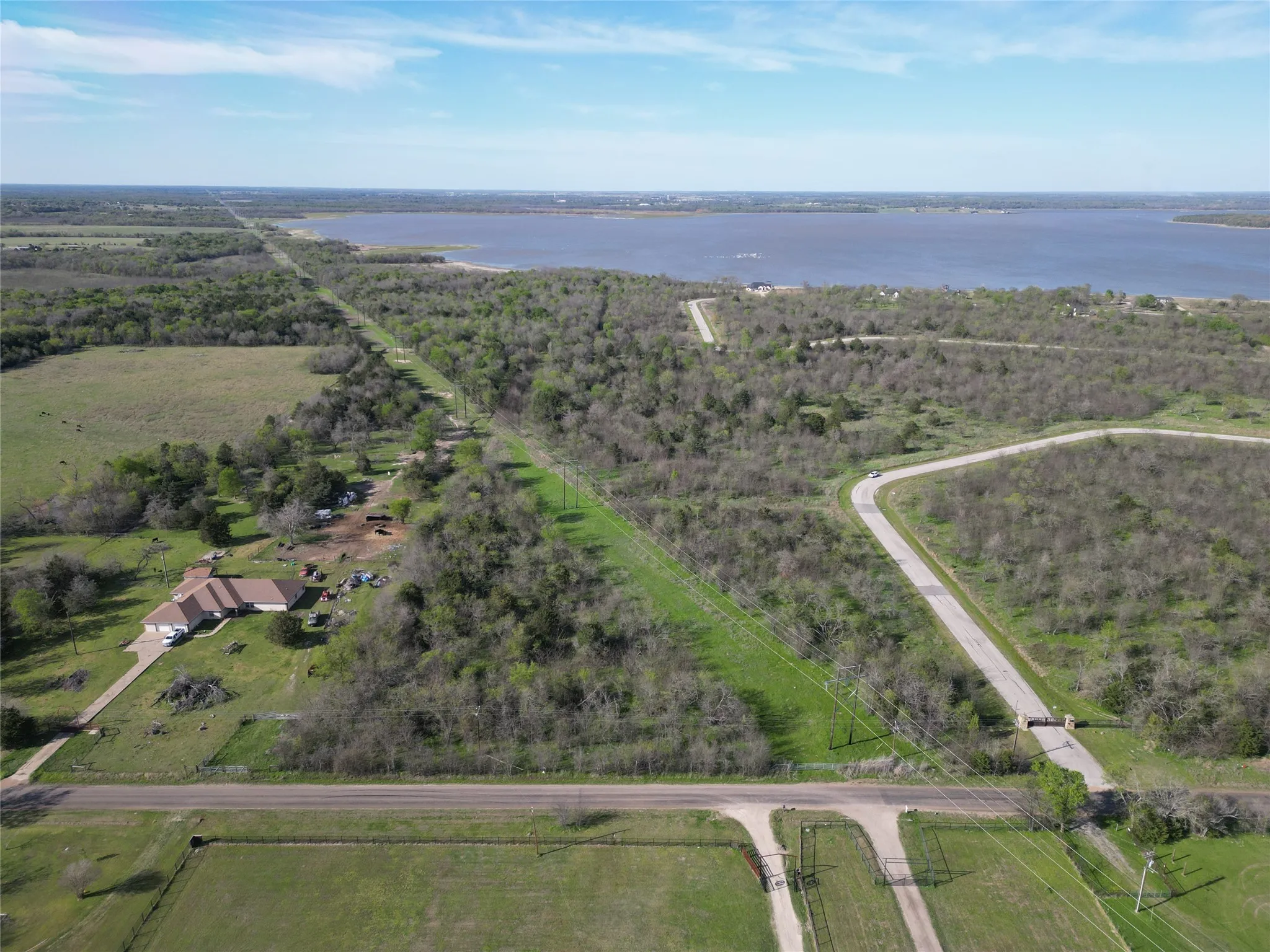 Expansive undeveloped land featuring a private paved road, perimeter fencing, and established treelines