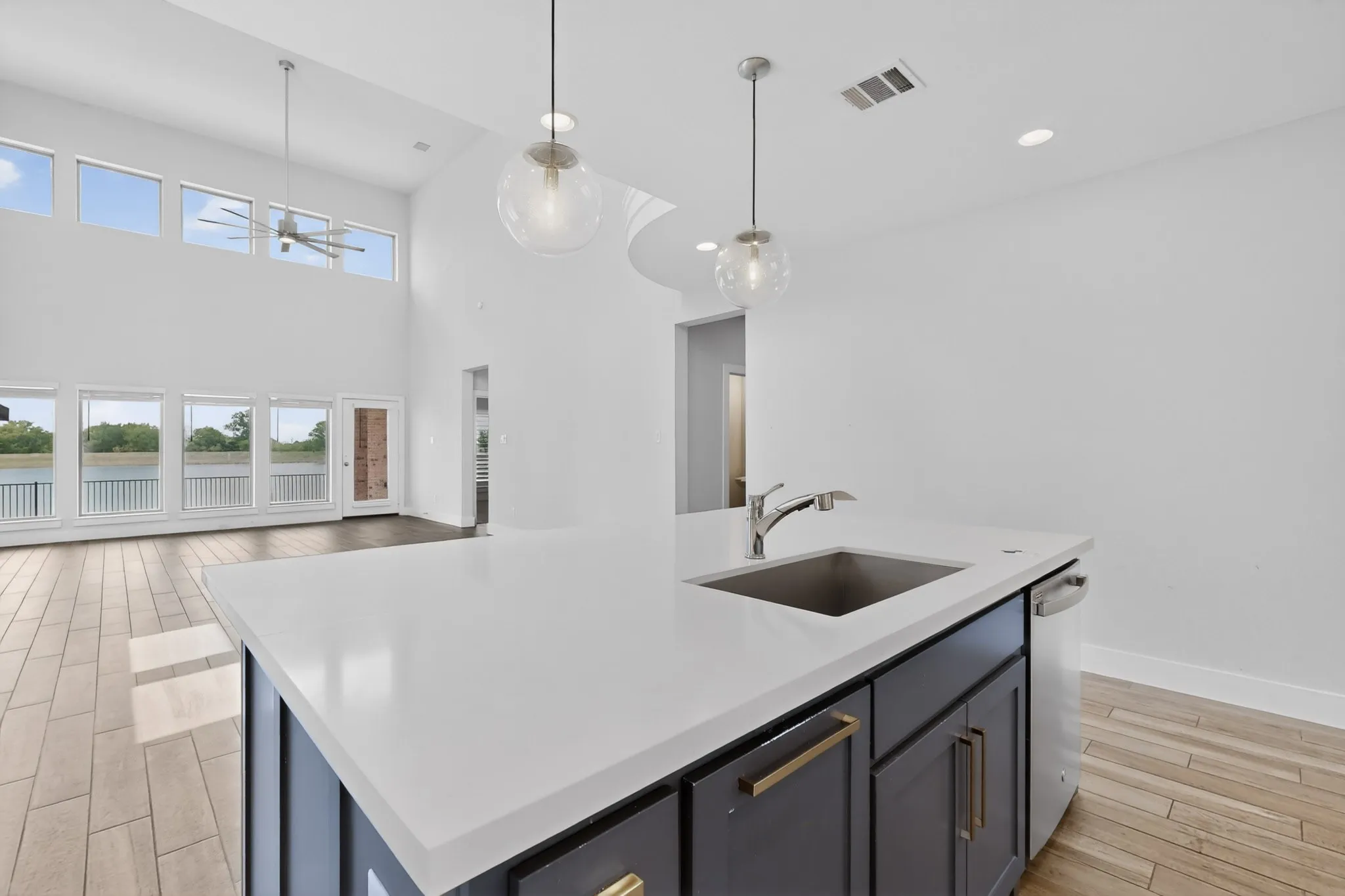 Kitchen island featuring a white countertop, undermount sink, and dark cabinetry with brass hardware