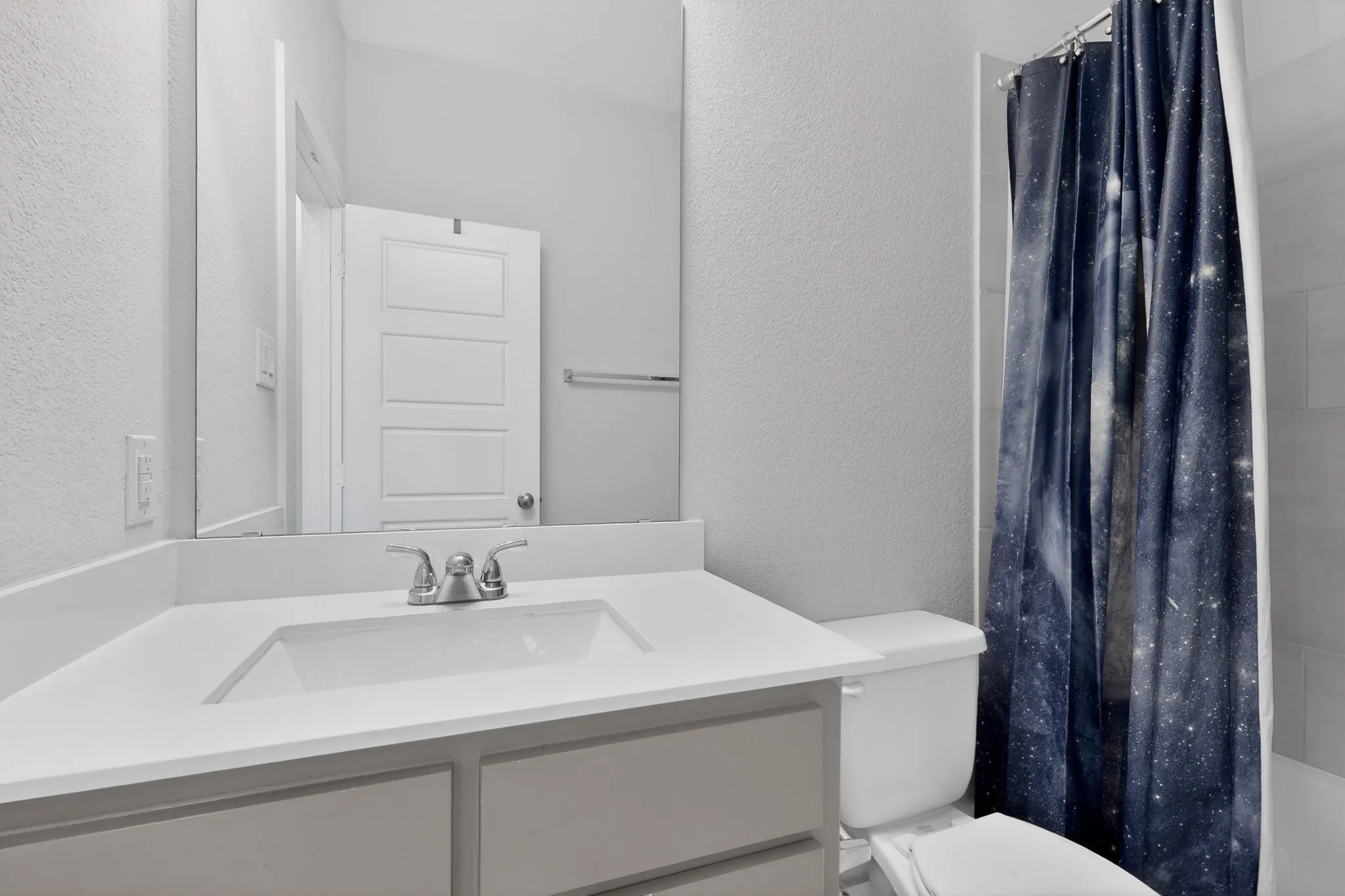Bathroom vanity featuring a single basin sink, chrome faucet, and white countertop