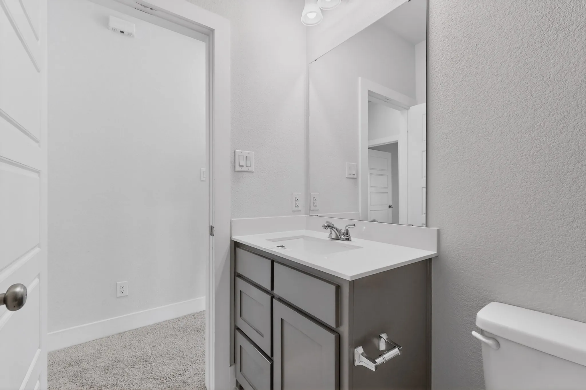 Contemporary bathroom vanity featuring a light-colored countertop, integrated sink, and chrome-finish faucet