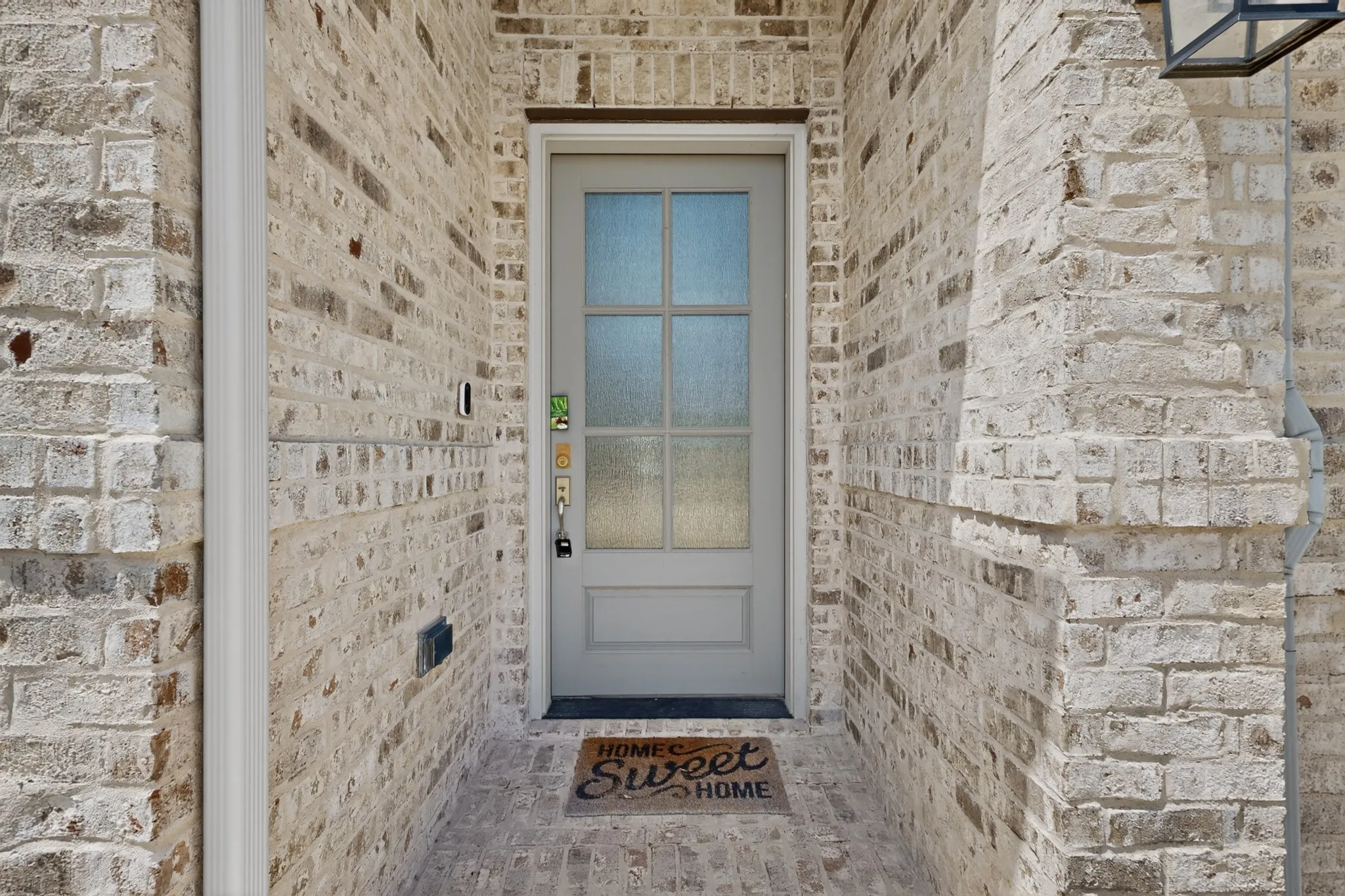 Entryway featuring light-toned brick, a paneled door with frosted glass inserts, and a coordinating brick porch