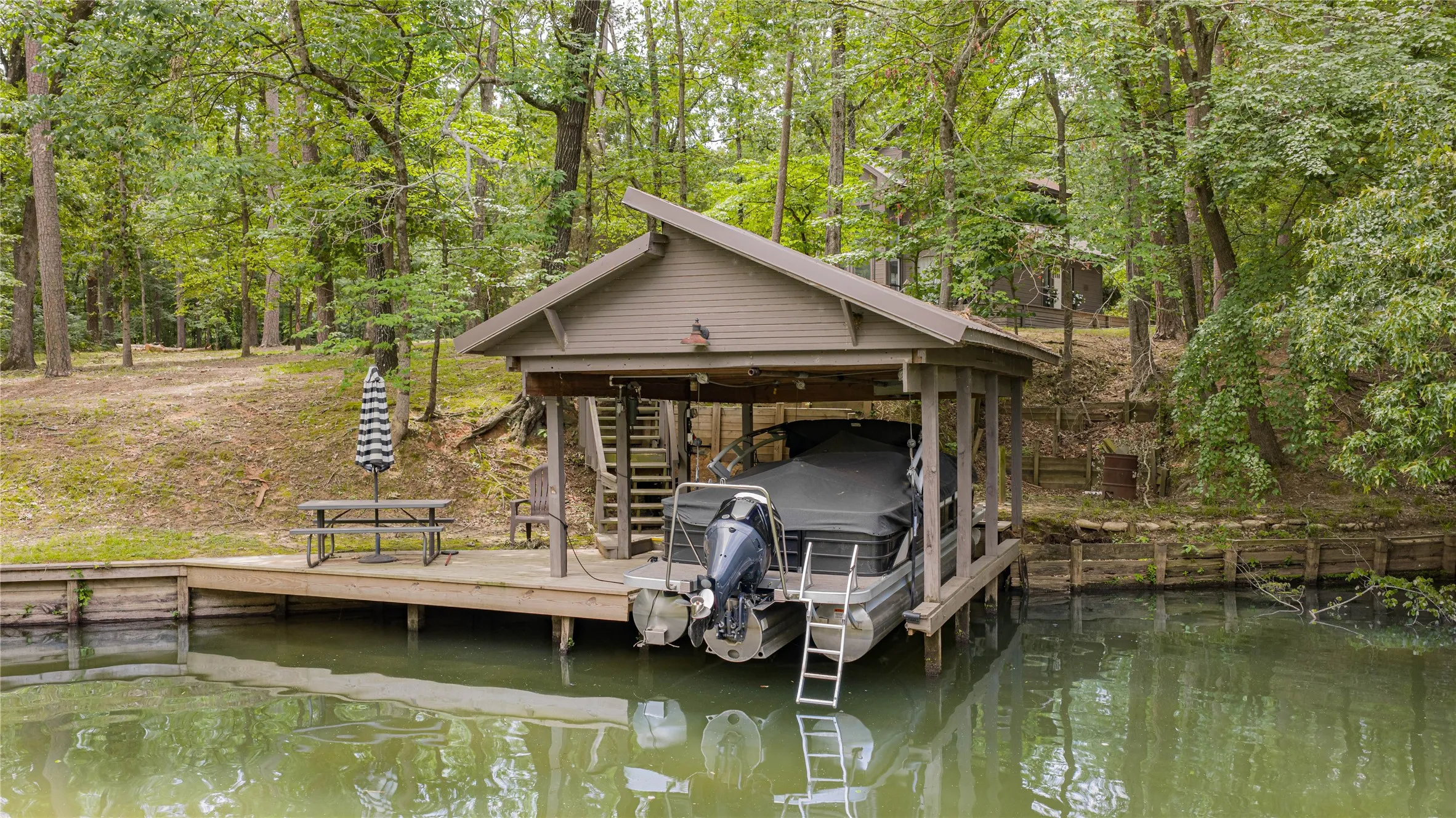 Covered boat dock featuring a wood-finish deck and integrated stairs