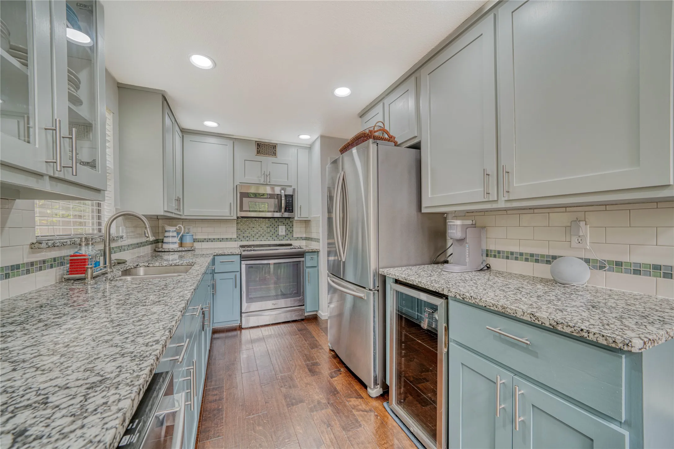 Kitchen featuring wood-finish flooring, two-tone cabinetry with brushed nickel hardware, and granite countertops