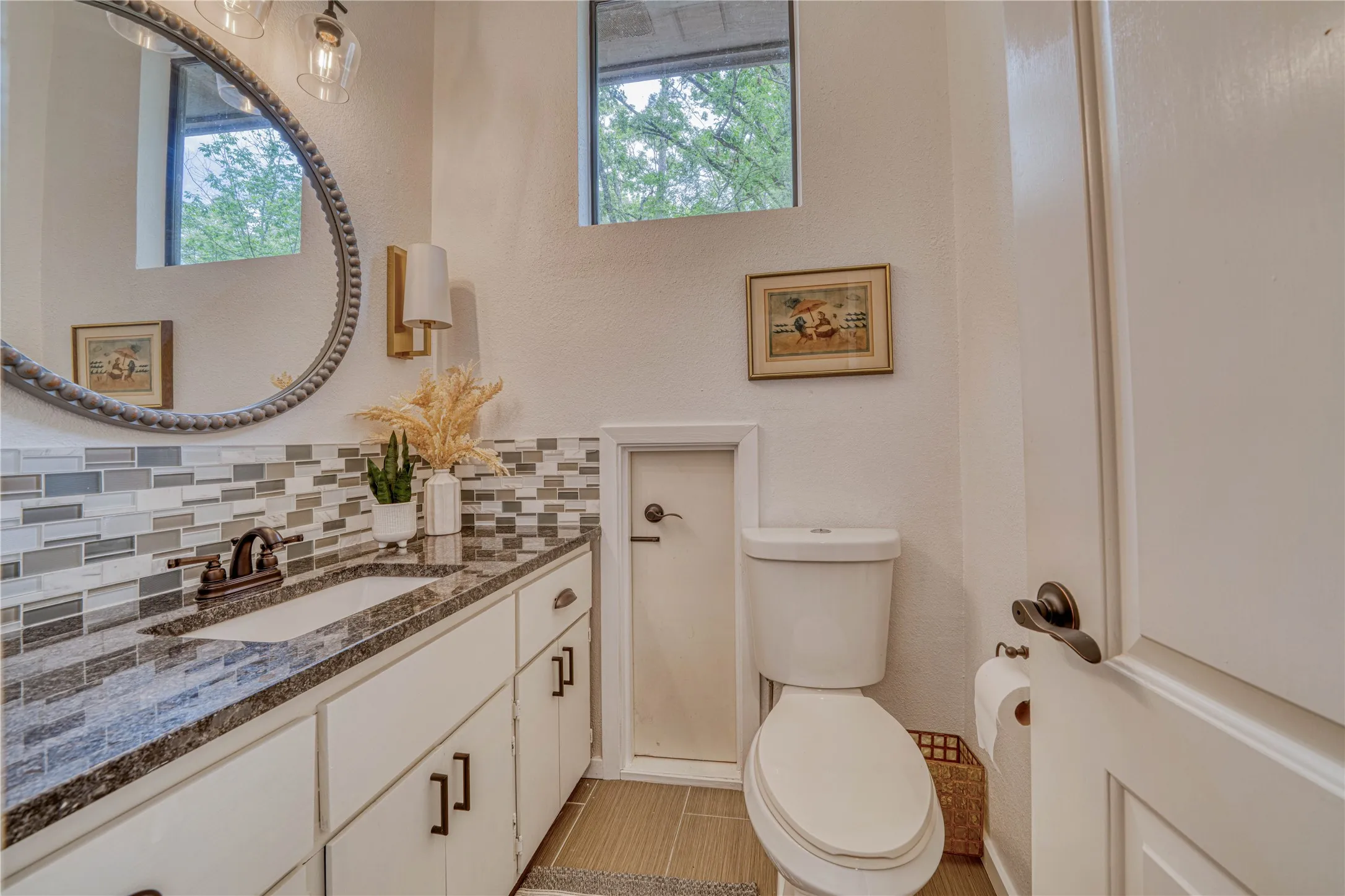 Bathroom vanity featuring a dark speckled countertop, undermount sink, and a multi-tone mosaic tile backsplash