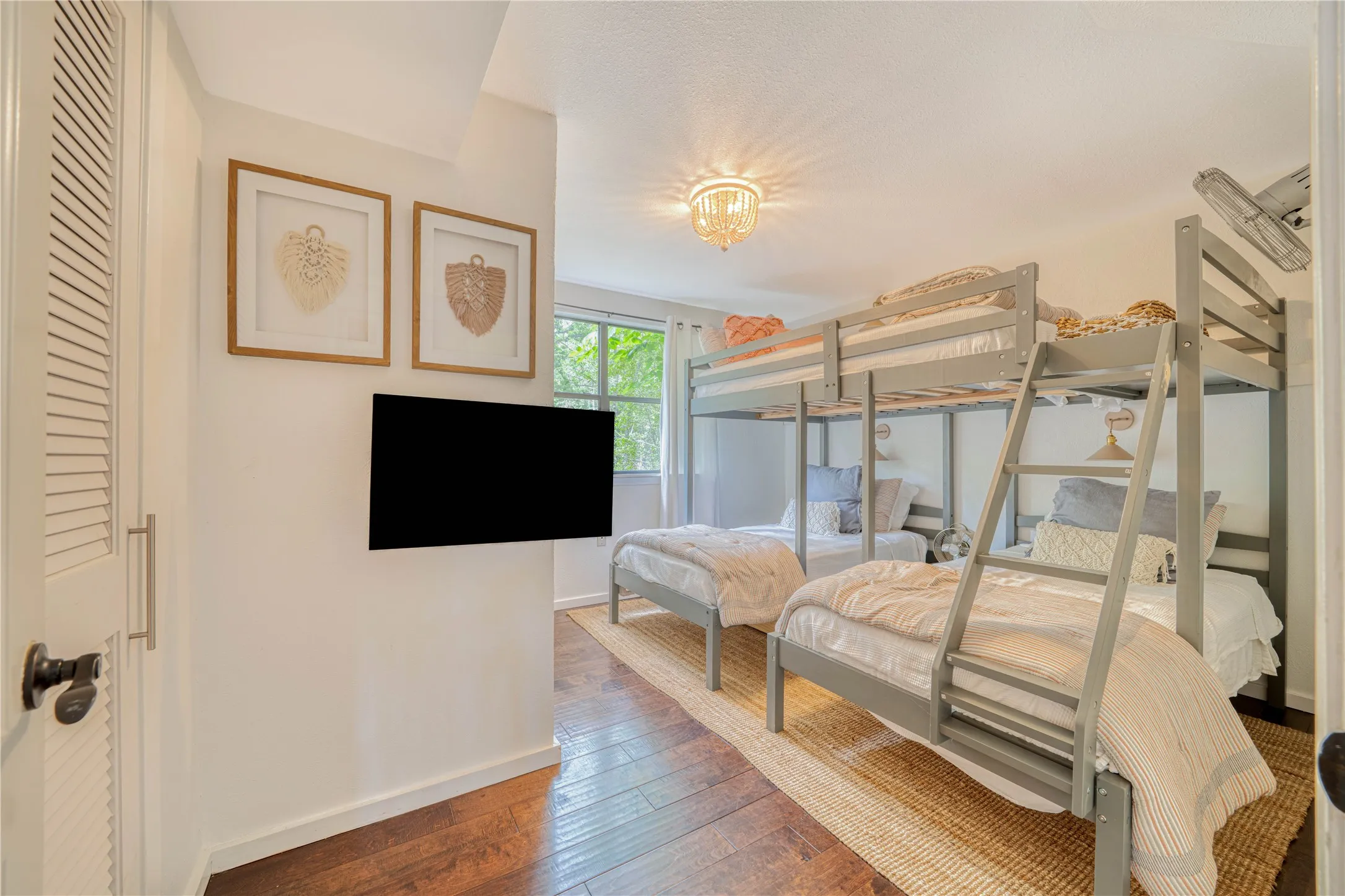 Room featuring wood-finish flooring, white walls, and a multi-tiered bunk bed structure