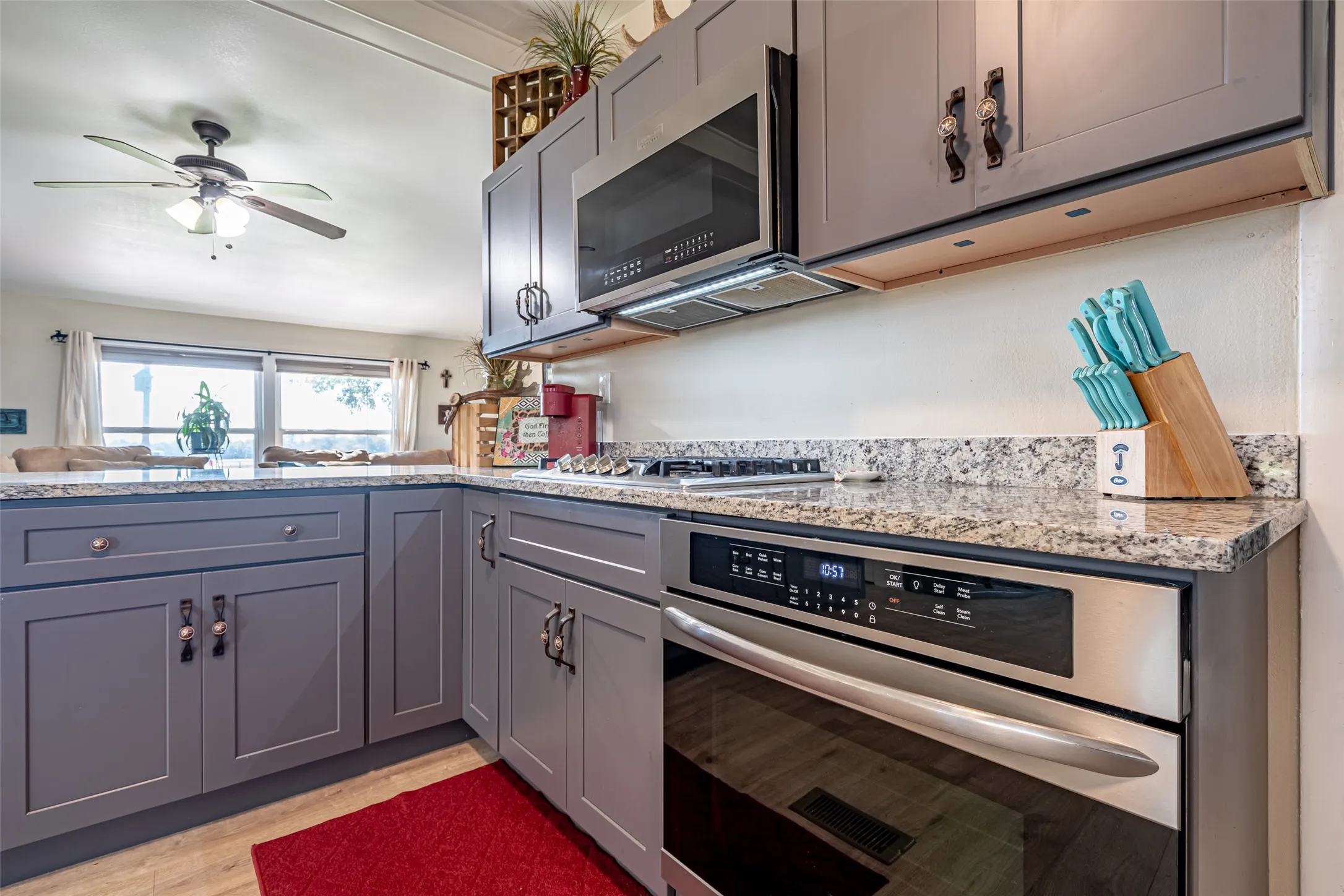 Kitchen featuring stainless steel appliances, gray cabinetry, light stone countertops, and light wood-type flooring. Fridge is EXCLUDED.