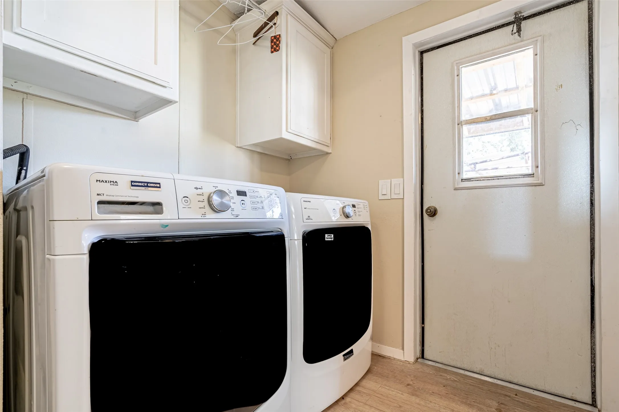 Laundry area featuring cabinet space, light wood-style floors.