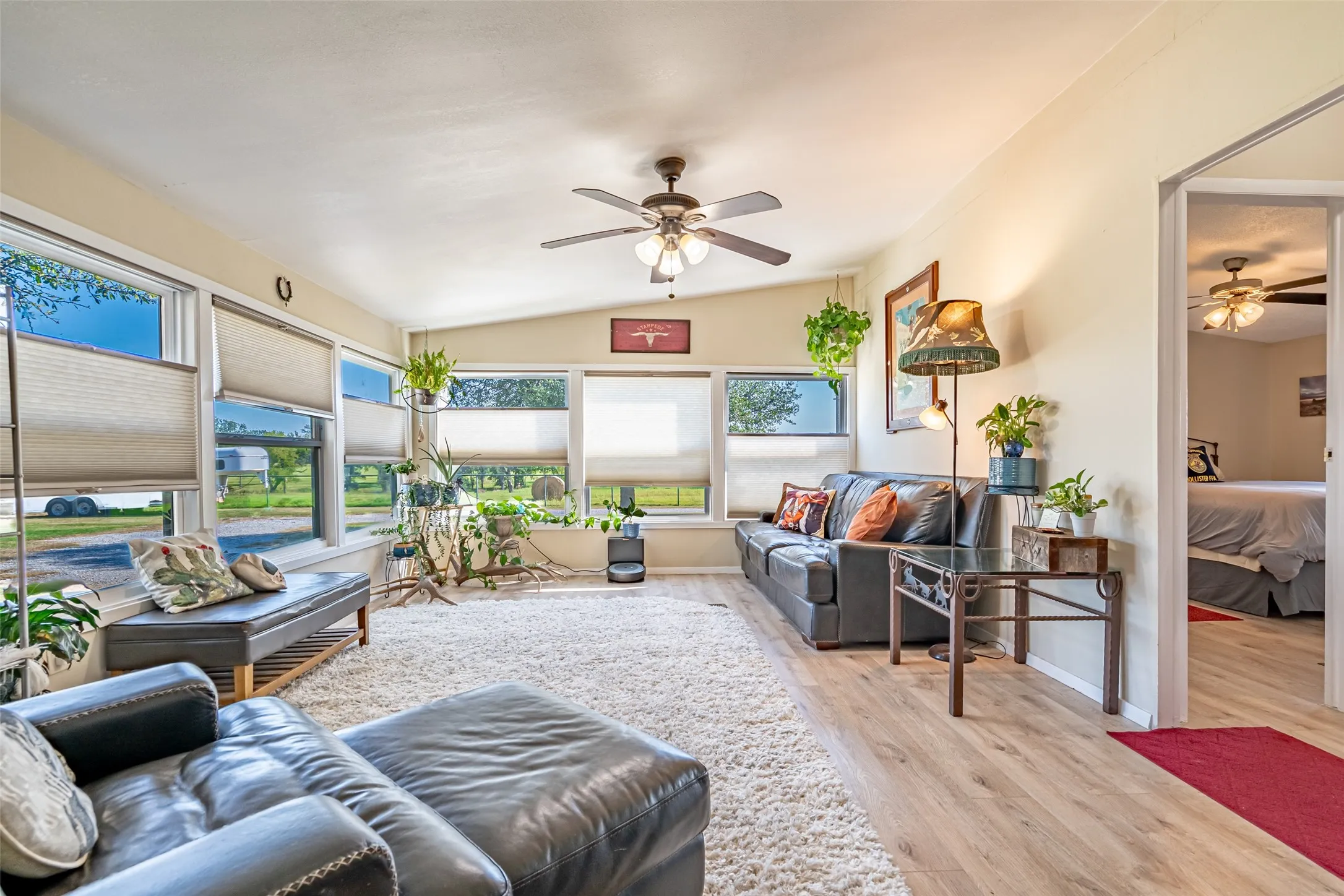Living room with light wood-type flooring, ceiling fan, and lofted ceiling.