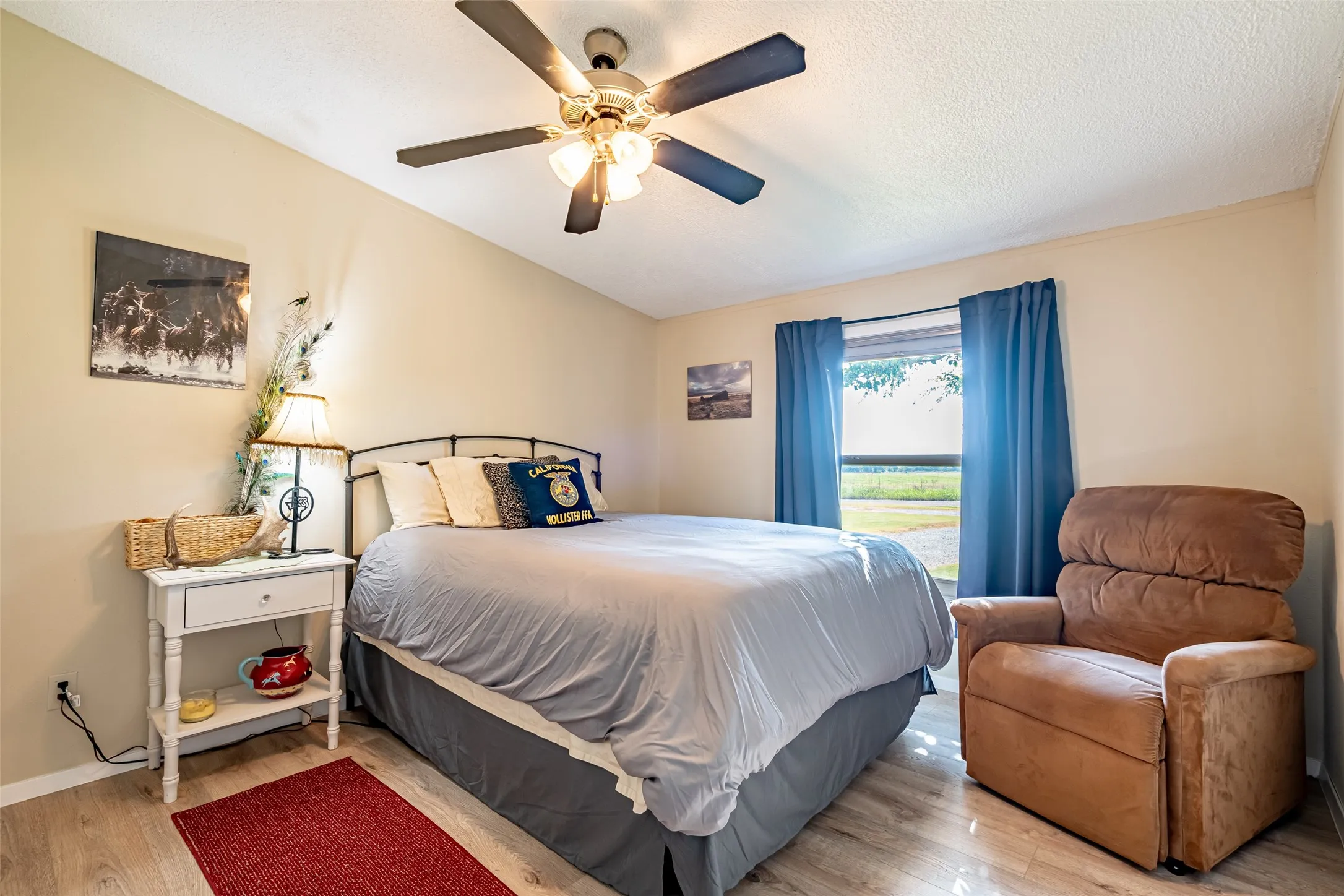 Bedroom with wood style floors, ceiling fan, and a textured ceiling.
