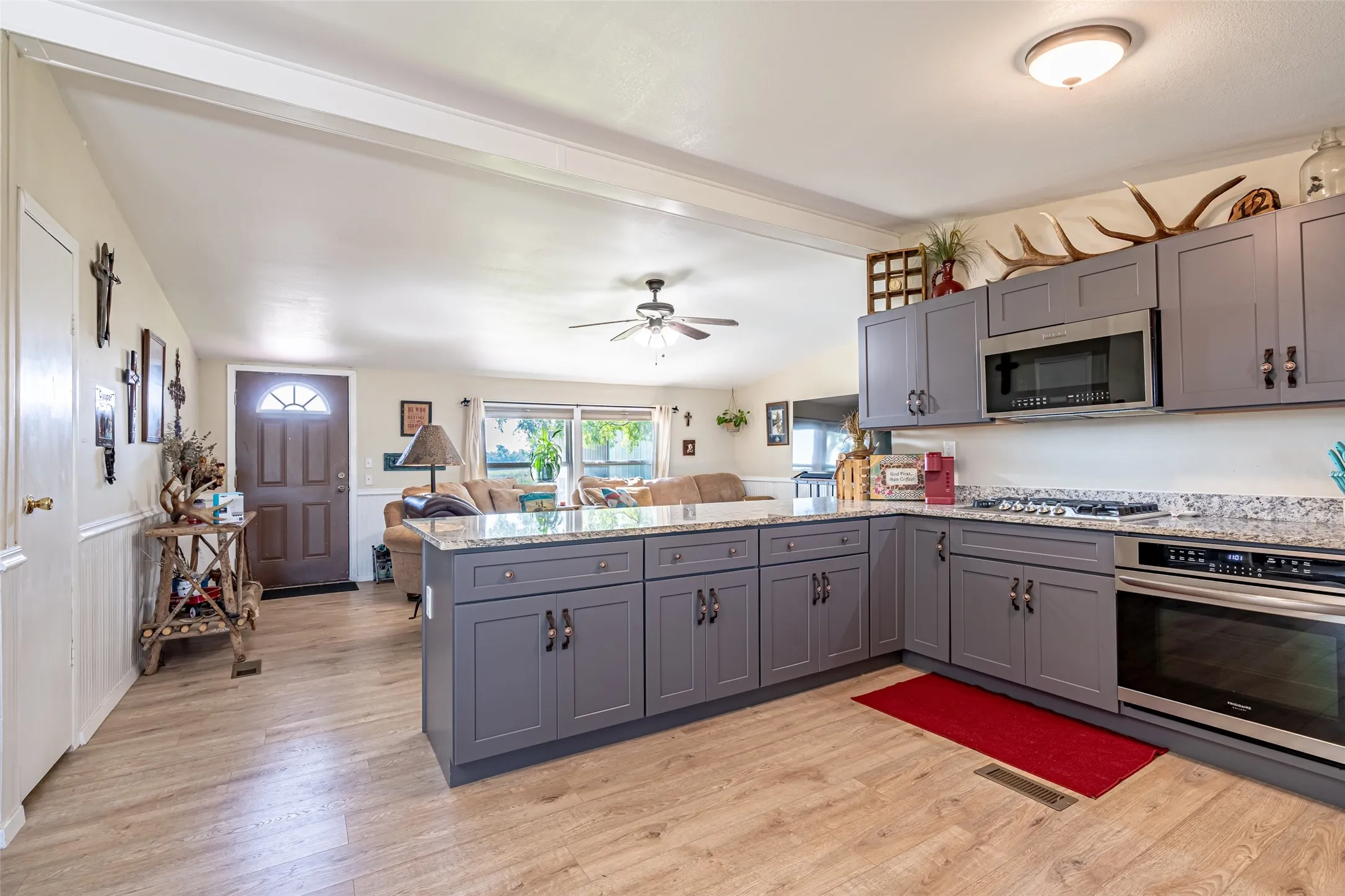 Kitchen with open floor plan, appliances with stainless steel finishes, light stone counters, a peninsula, and gray cabinets. Fridge is EXCLUDED.