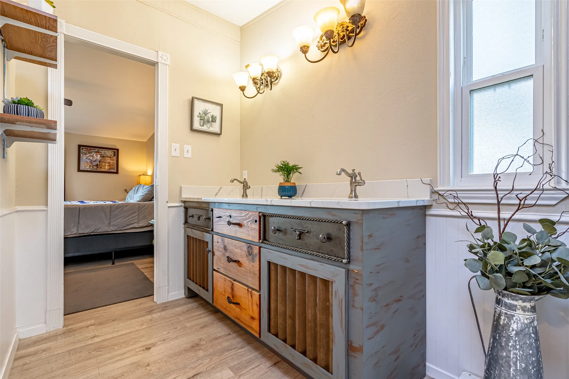 Ensuite bathroom with double vanity and light wood-type flooring.