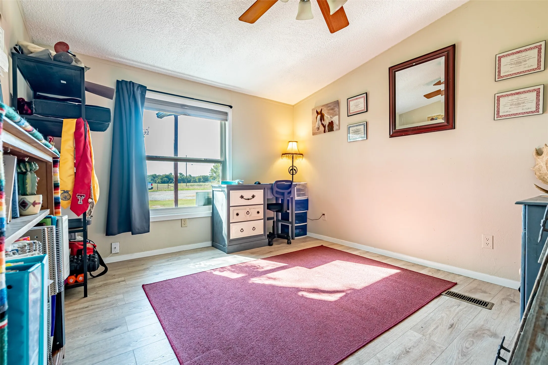 Third bedroom featuring a textured ceiling, light wood-style floors, and a ceiling fan.