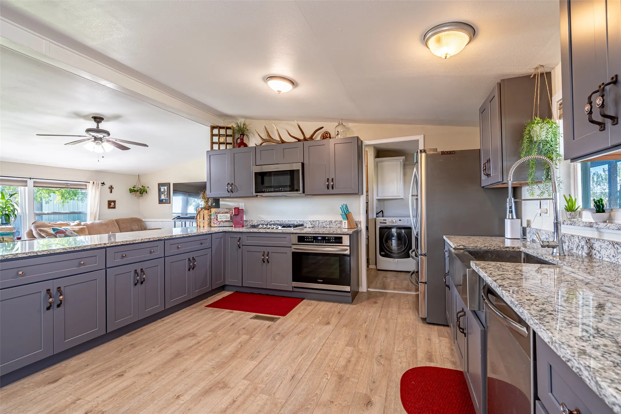 Kitchen with gray cabinetry, light stone counters, and light wood-style flooring. Fridge is EXCLUDED.