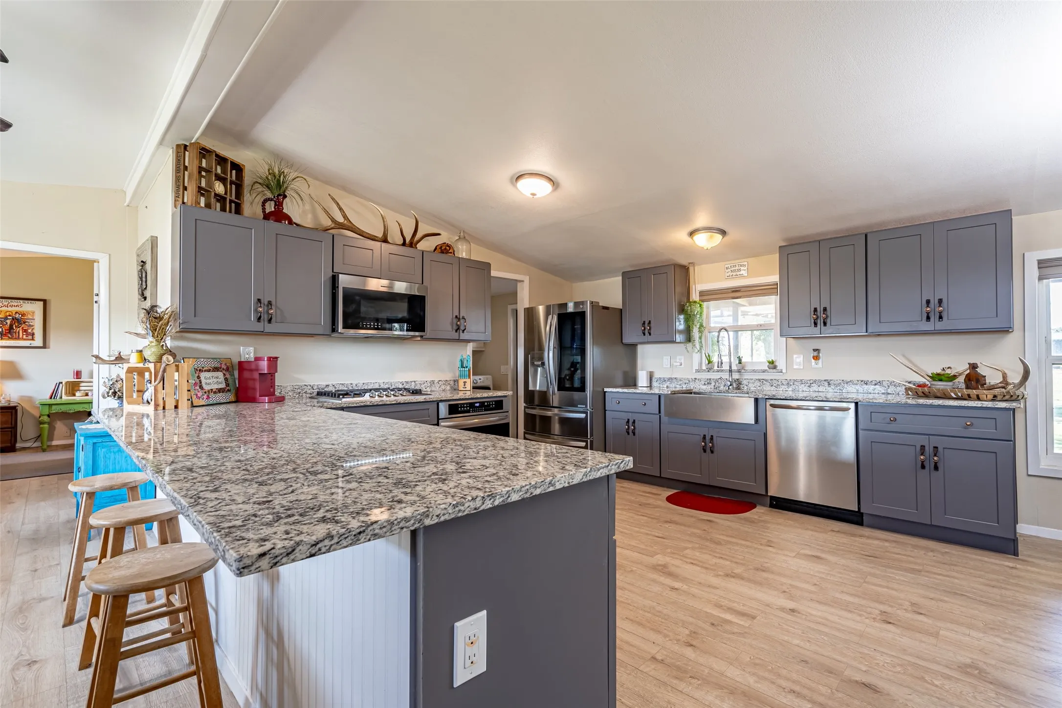 Kitchen featuring a kitchen bar, light wood-style flooring, a peninsula, gray cabinets, and vaulted ceiling. Fridge is EXCLUDED.