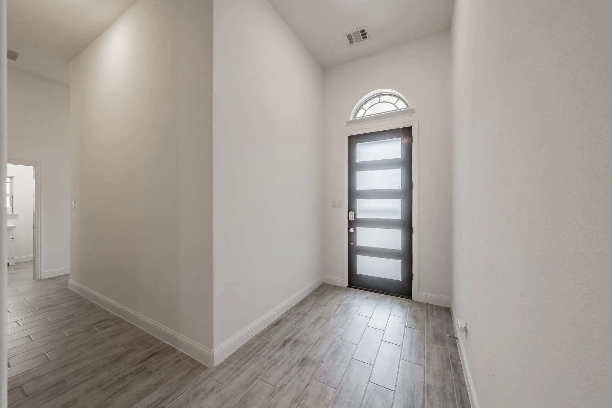Foyer entrance featuring tile wood-style floors and contemporary front door lets in all the sunshine without the heat!