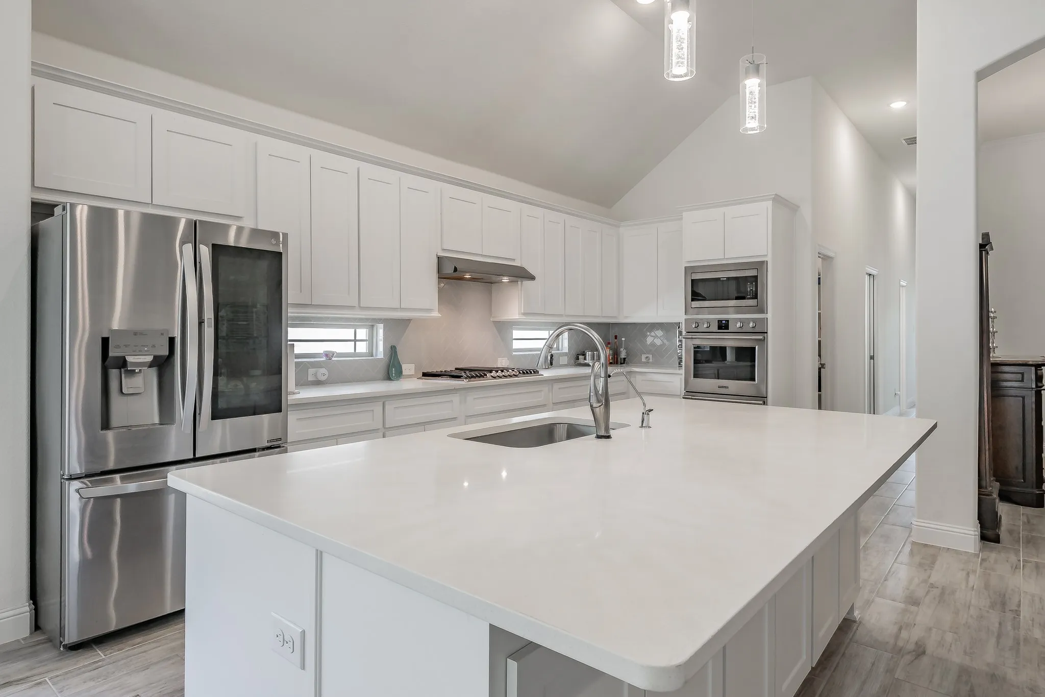 Kitchen with stainless steel appliances, an island with sink, white cabinetry, and sink