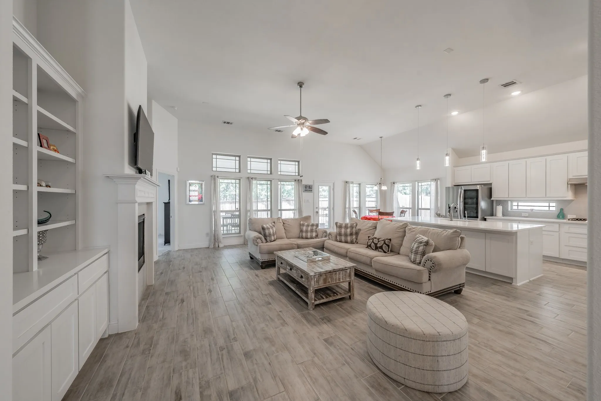 Open concept featuring light wood-type tile flooring, high vaulted ceiling, and ceiling fan