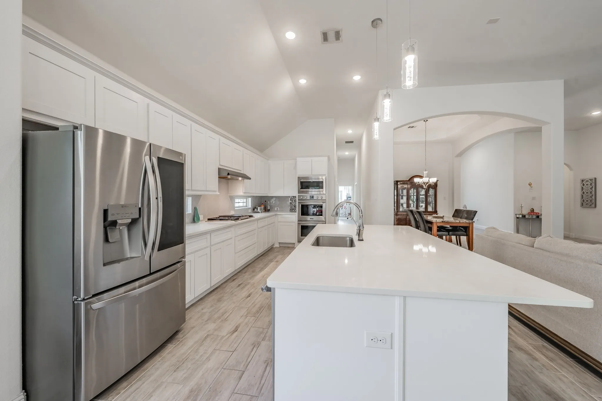 Kitchen featuring an island with sink, appliances with stainless steel finishes, and white cabinets. Refrigerator does not convey
