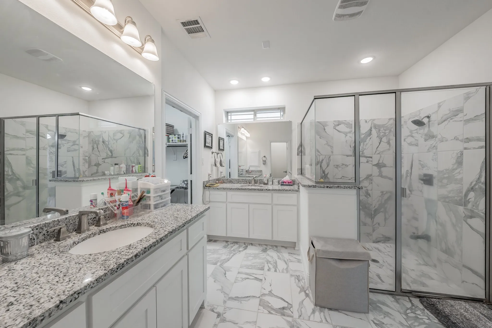 Bathroom featuring a shower with door and dual vanities