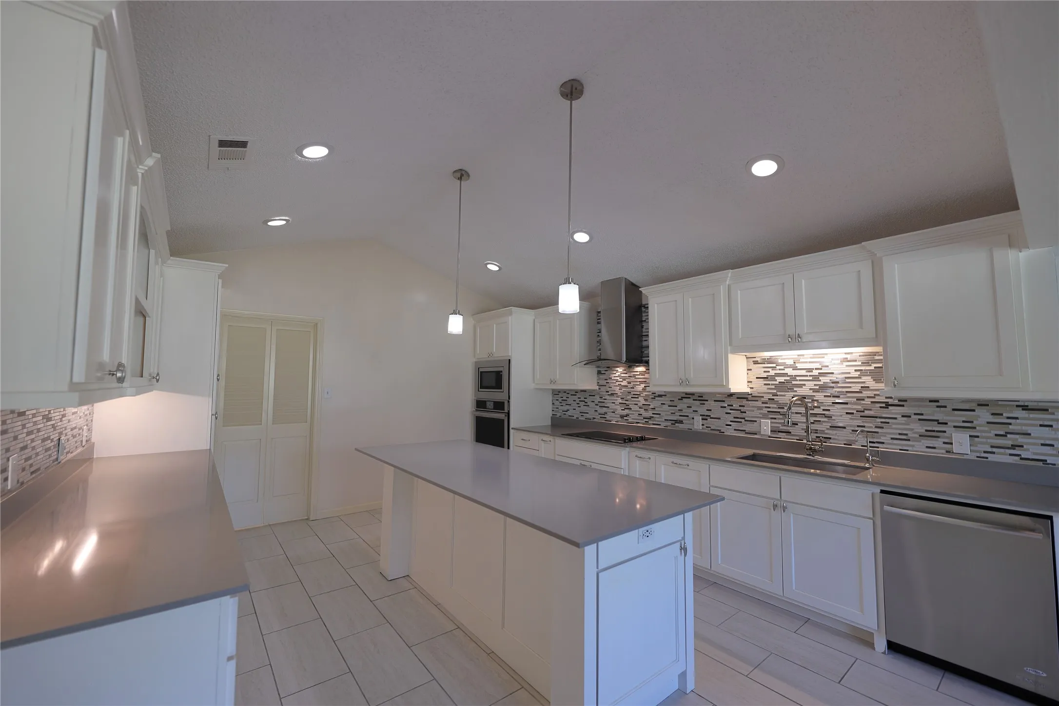 Kitchen featuring white cabinetry, a central island, stainless steel appliances, recessed lighting, and a mosaic tile backsplash