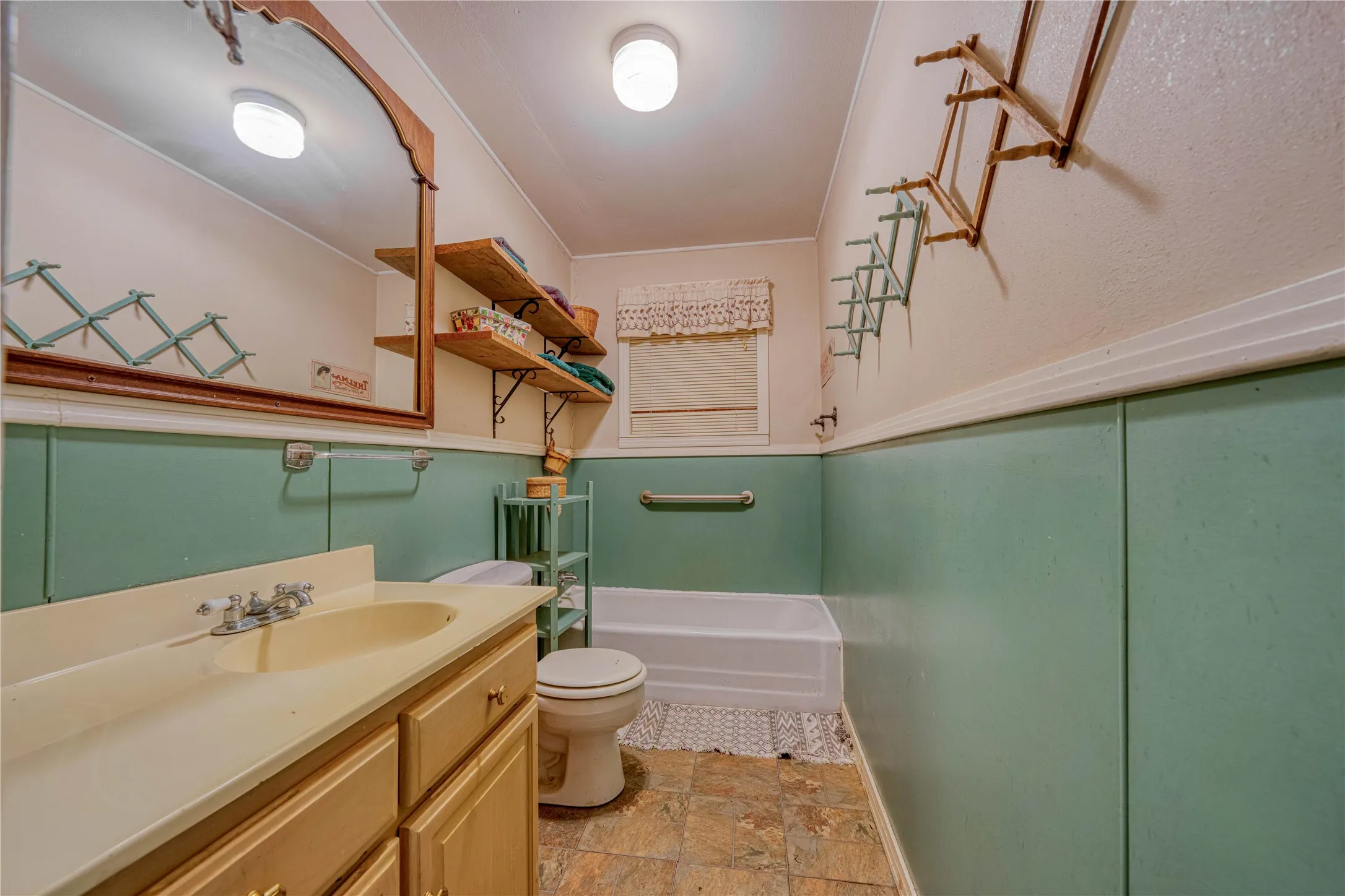 cottage Bathroom featuring a single vanity with a laminate countertop, light wood-finish cabinetry, and a full-size bathtub