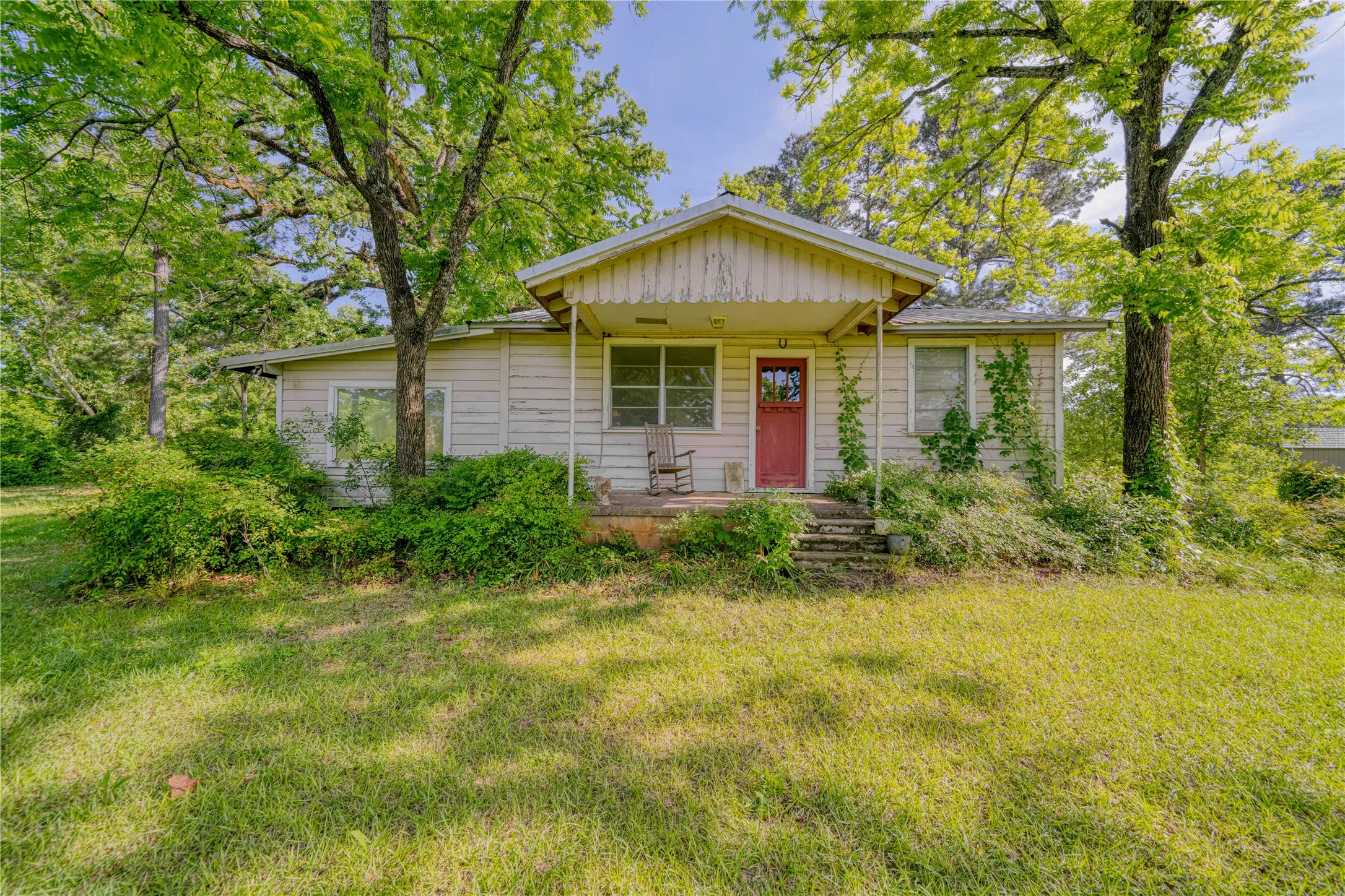 Single-story cottage is redeemable even in its rugged state... it is habitable with 2 window units, metal roof, kitchen, bedroom/bath